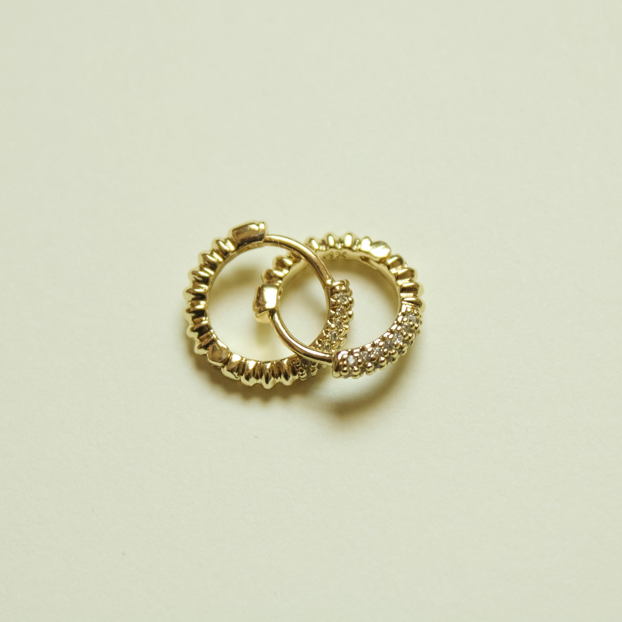 Dainty Pavé CZ Huggie Hoop Earrings Gold — pair overlapping flat lay on white