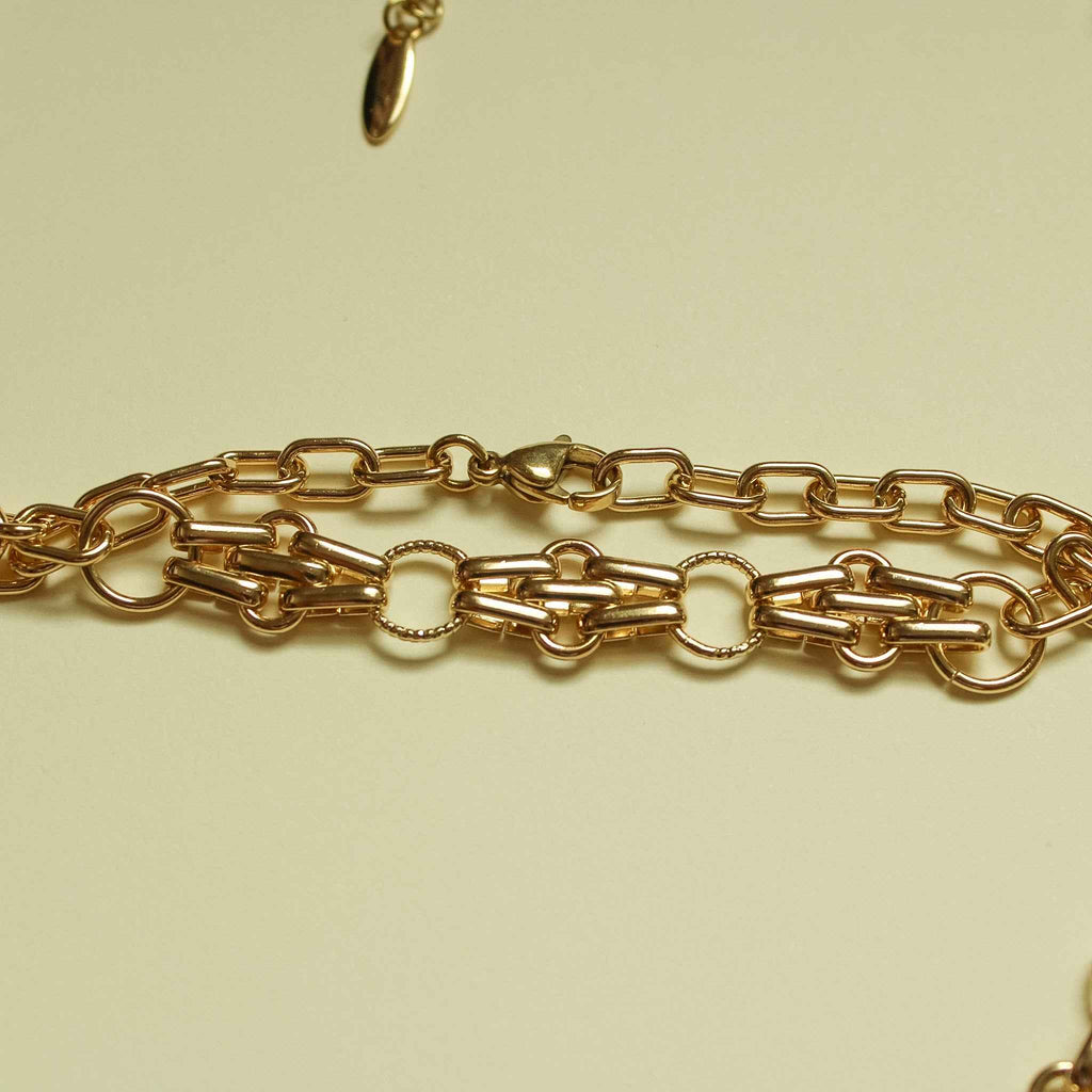Gold-plated bracelet chain with mixed link shapes and oval connector links, close-up