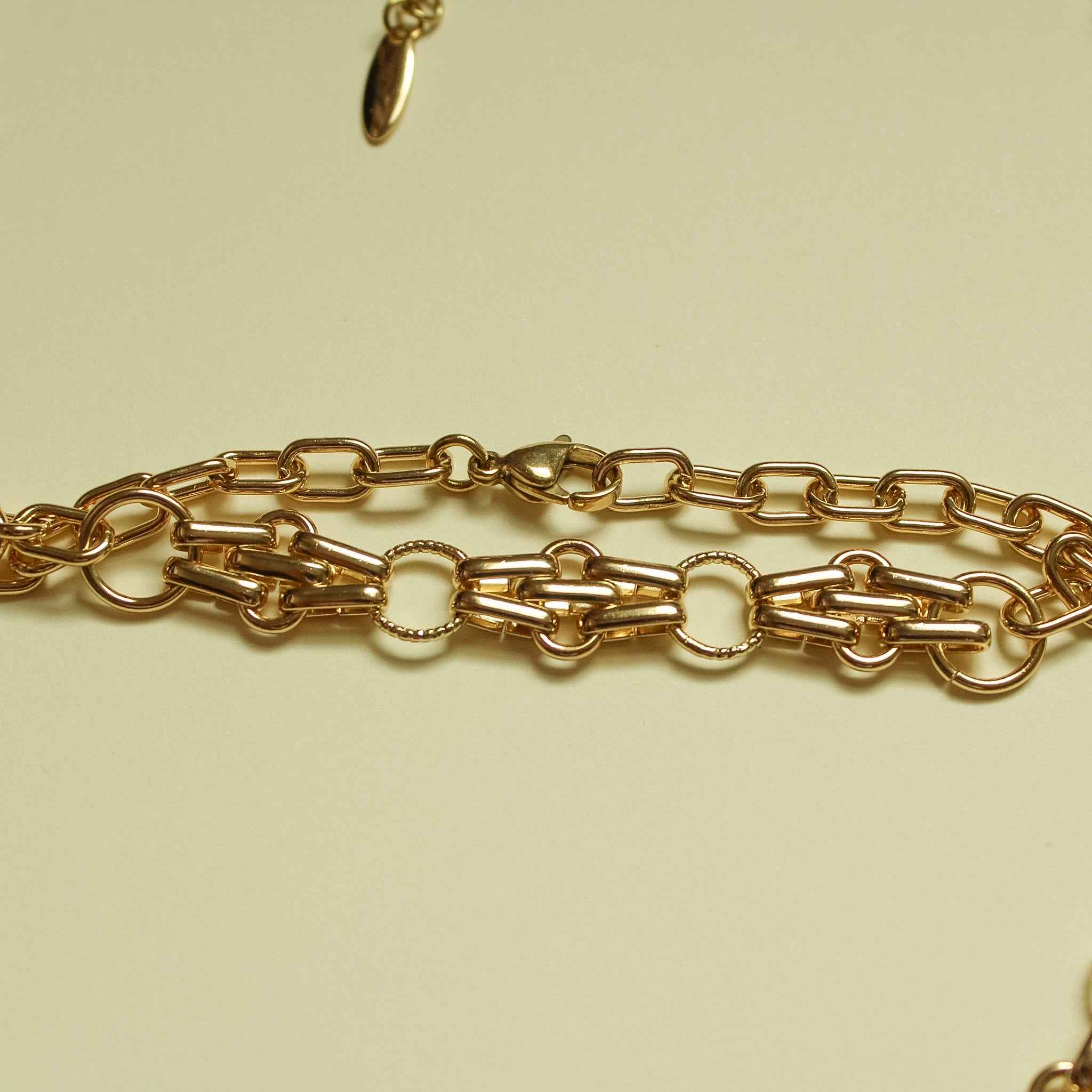 Gold-plated bracelet chain with mixed link shapes and oval connector links, close-up