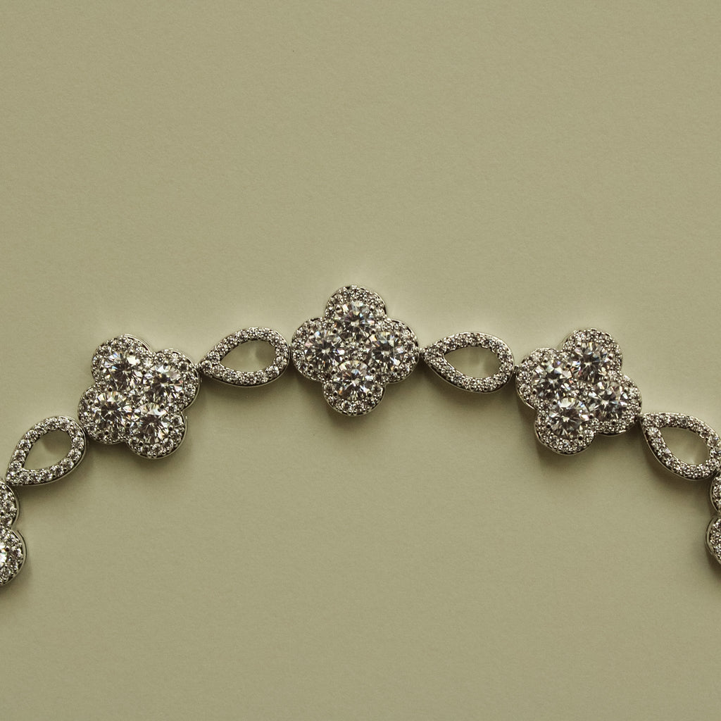 Close-up of silver-tone CZ clover bracelet section with oval spacer links