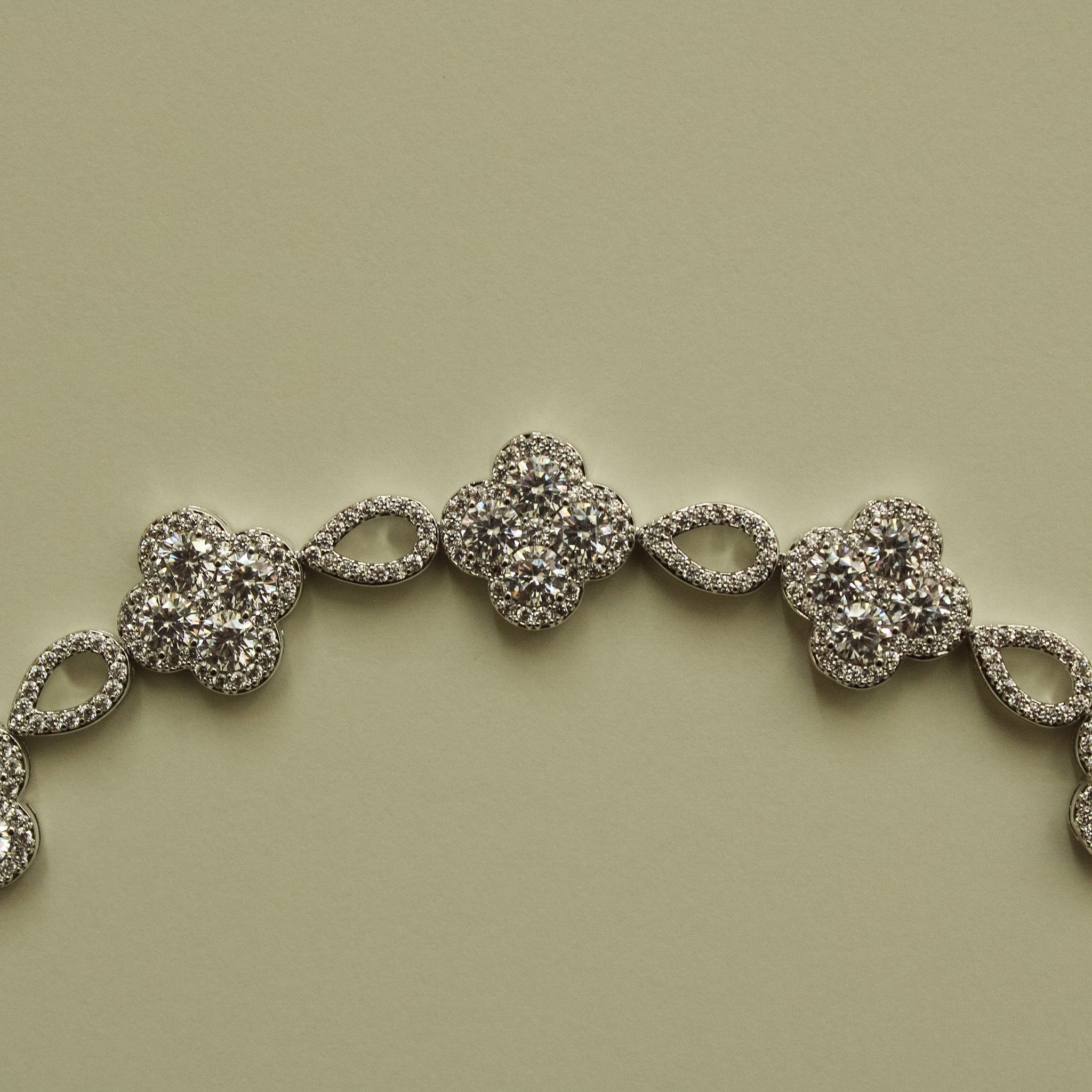 Close-up of silver-tone CZ clover bracelet section with oval spacer links
