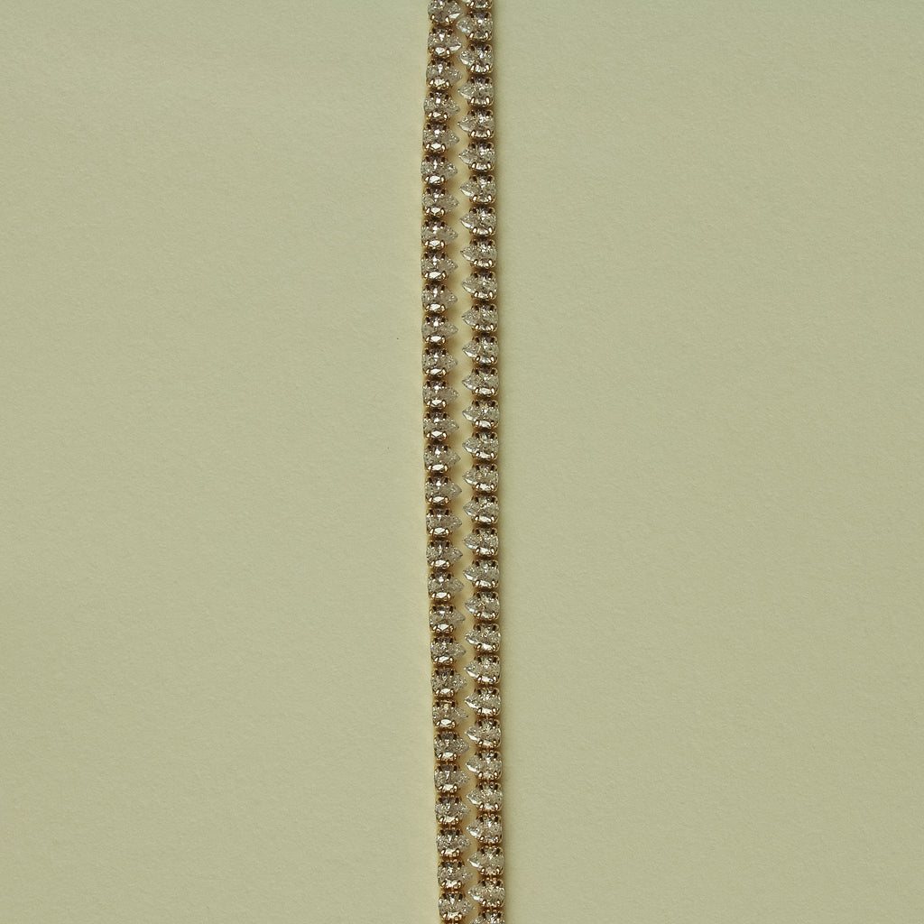 Gold-tone double-row tennis bracelet with clear CZ stones, close-up view.