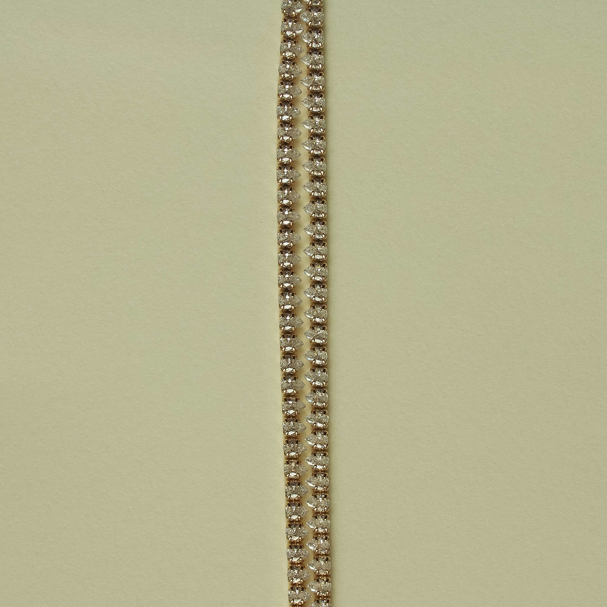 Gold-tone double-row tennis bracelet with clear CZ stones, close-up view.