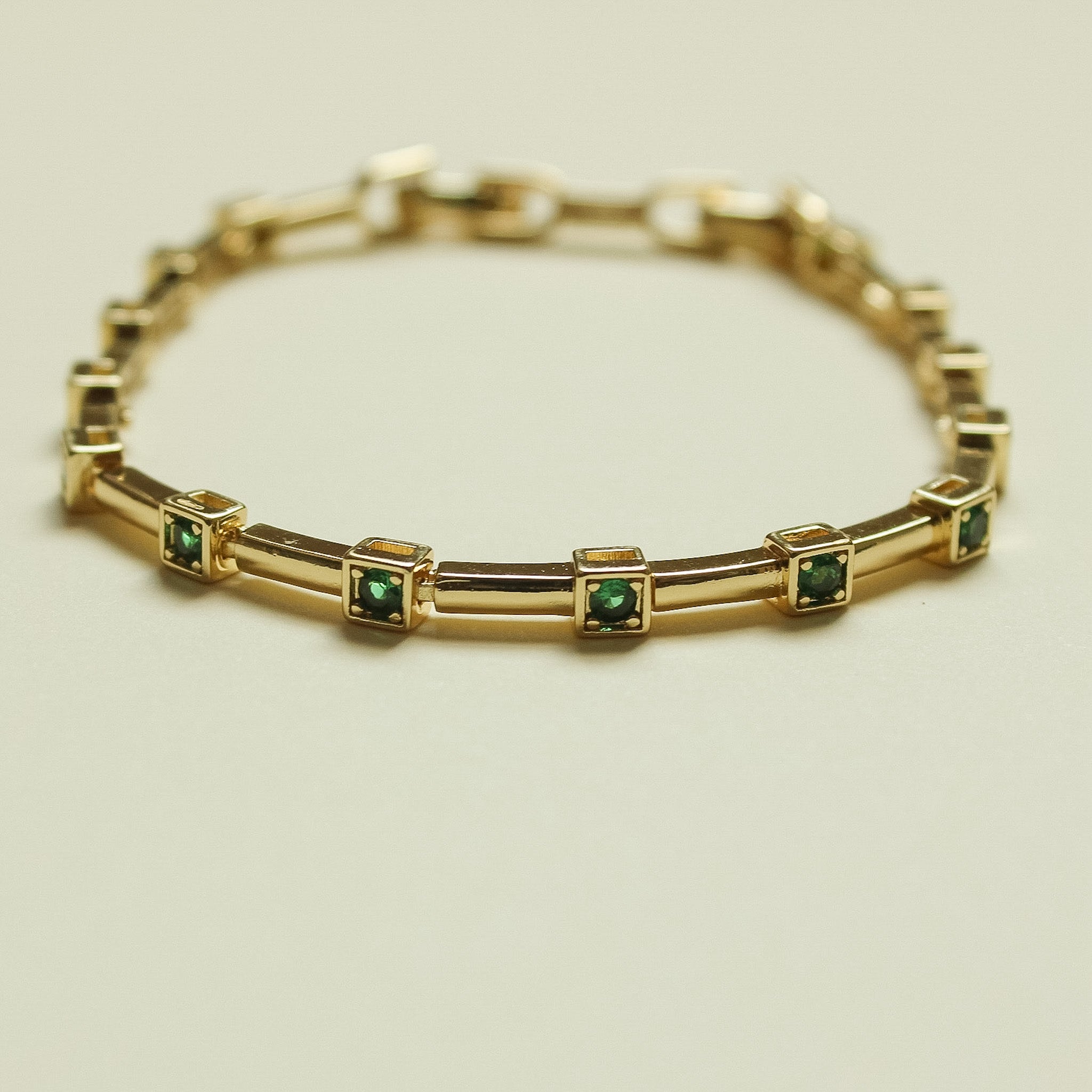 Gold-tone bar link bracelet with green square stones in bezel frames
