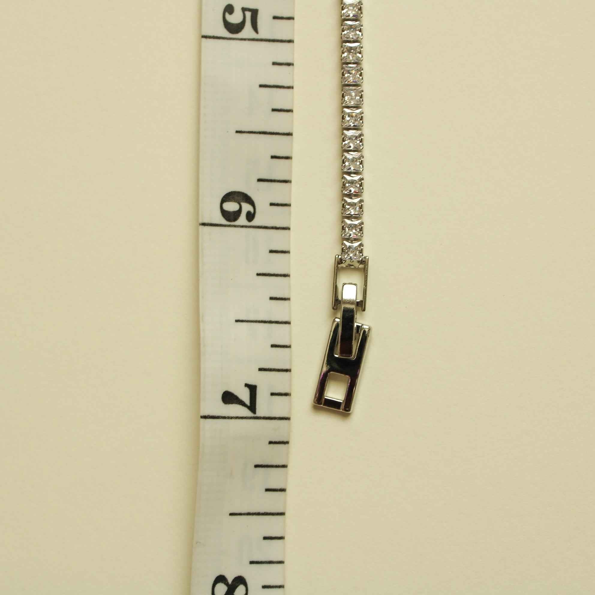 Silver tennis bracelet clasp detail with baguette stones and hook closure