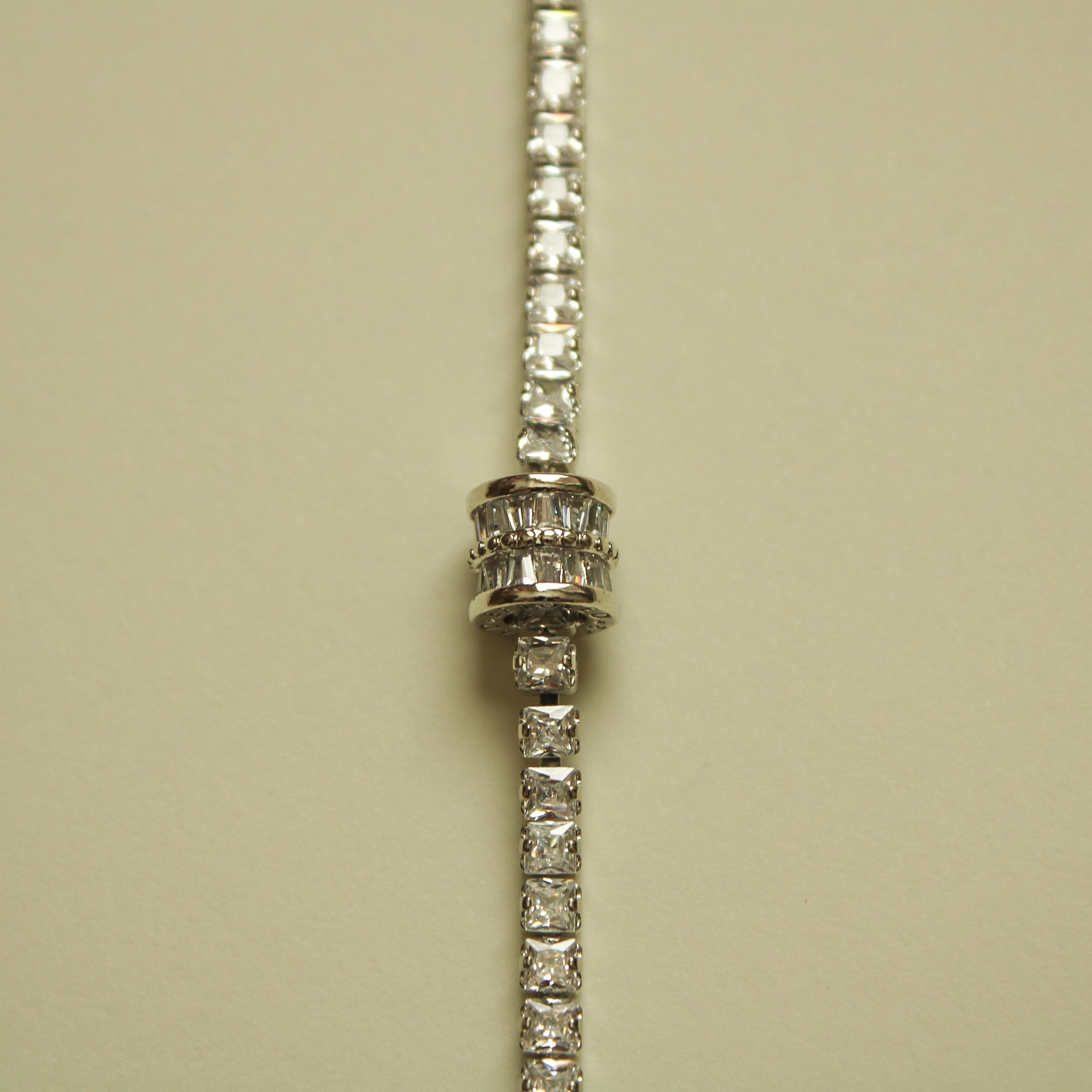 Silver tennis bracelet end with ridged barrel link and round clear stones