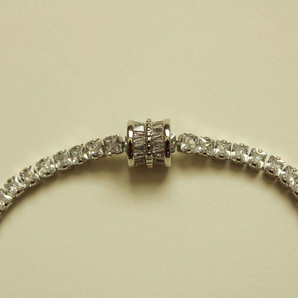 Silver tennis bracelet center with round clear stones and ridged barrel link