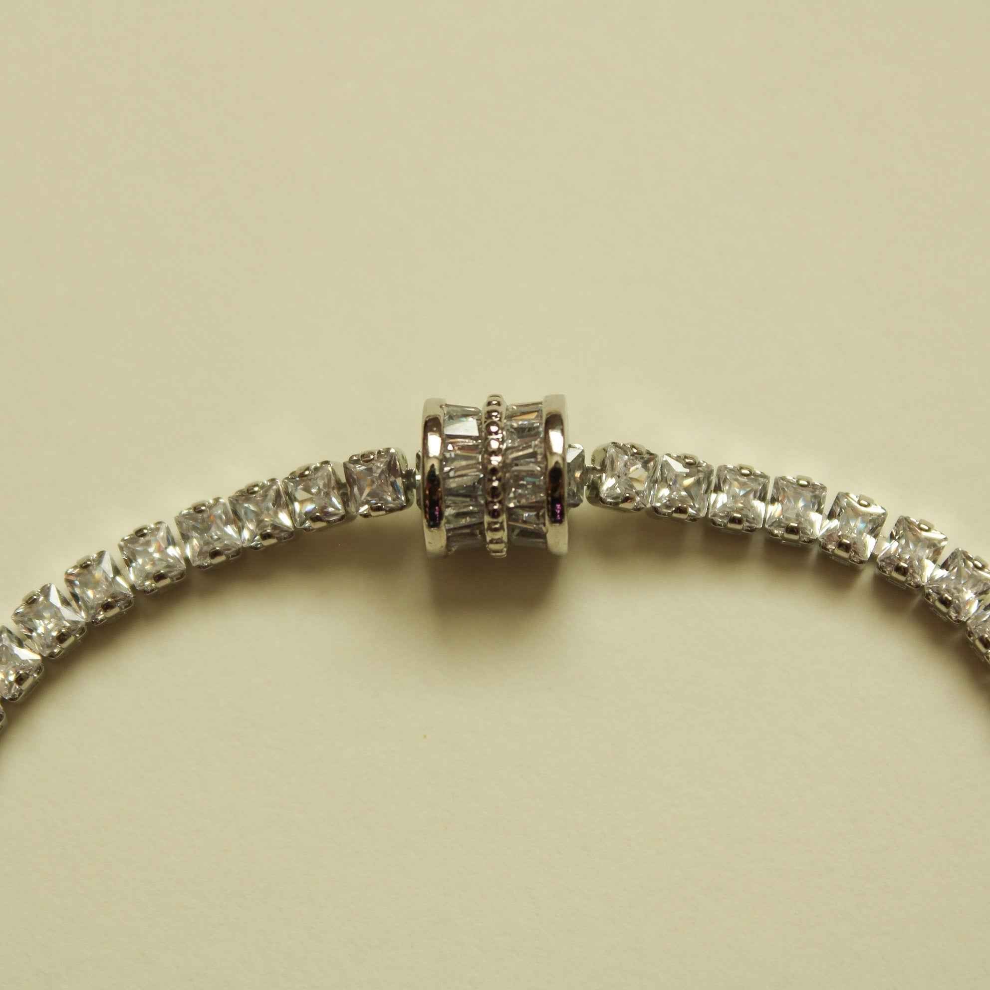 Silver tennis bracelet center with round clear stones and ridged barrel link
