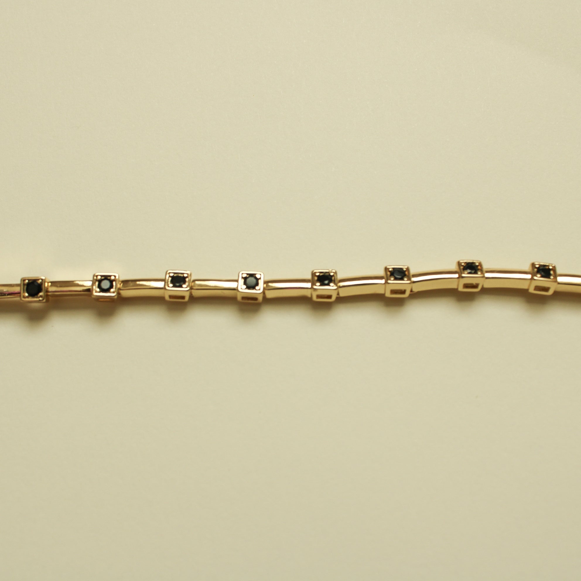 Gold bar bracelet with evenly spaced black CZ bezel links, straight view