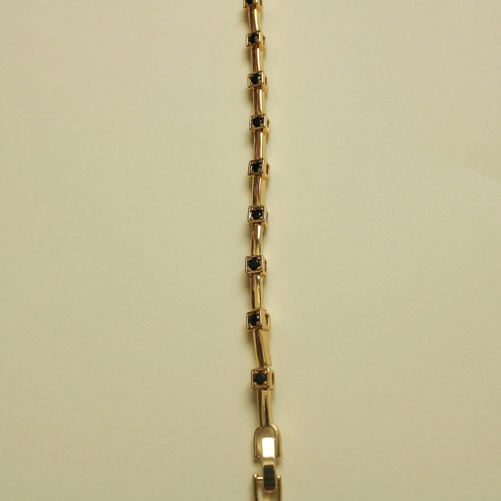 Gold bracelet chain with black CZ bezel stations on rectangular bar links, vertical view