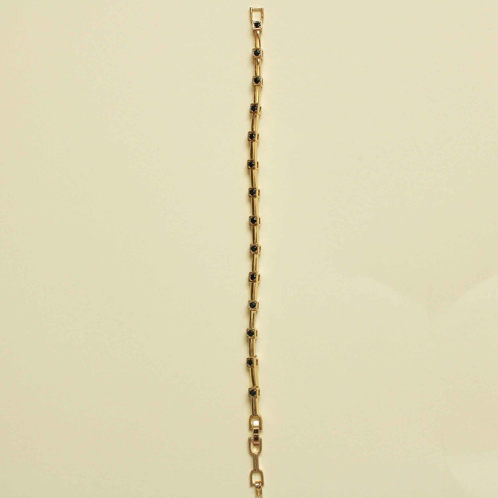 Gold bracelet with bar links and black CZ bezel stations along the chain, side view