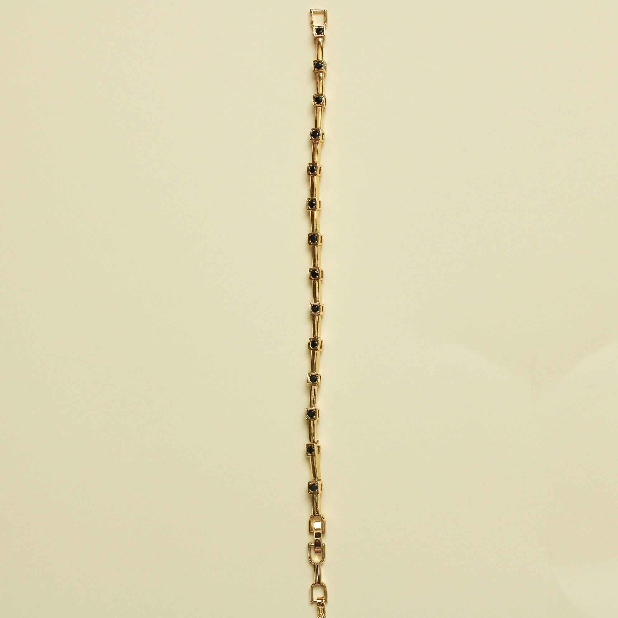 Gold bracelet with bar links and black CZ bezel stations along the chain, side view