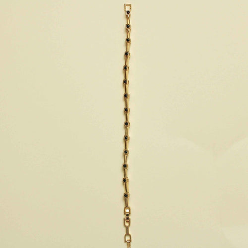 Gold bracelet with bar links and black CZ bezel stations along the chain, side view