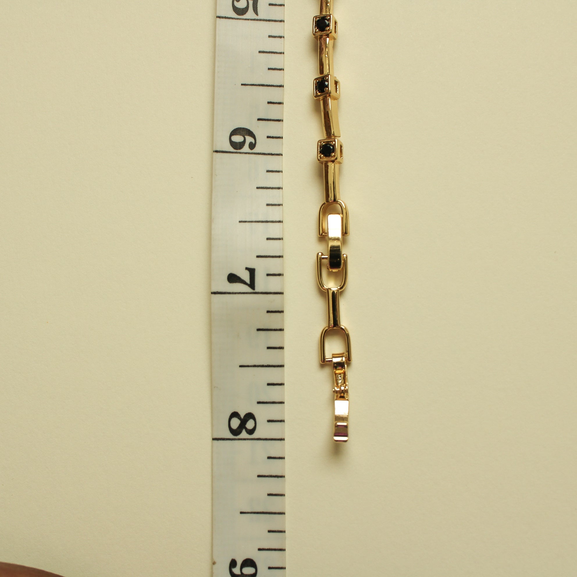 Gold bracelet link chain with small black CZ bezels on rectangular bars, close-up