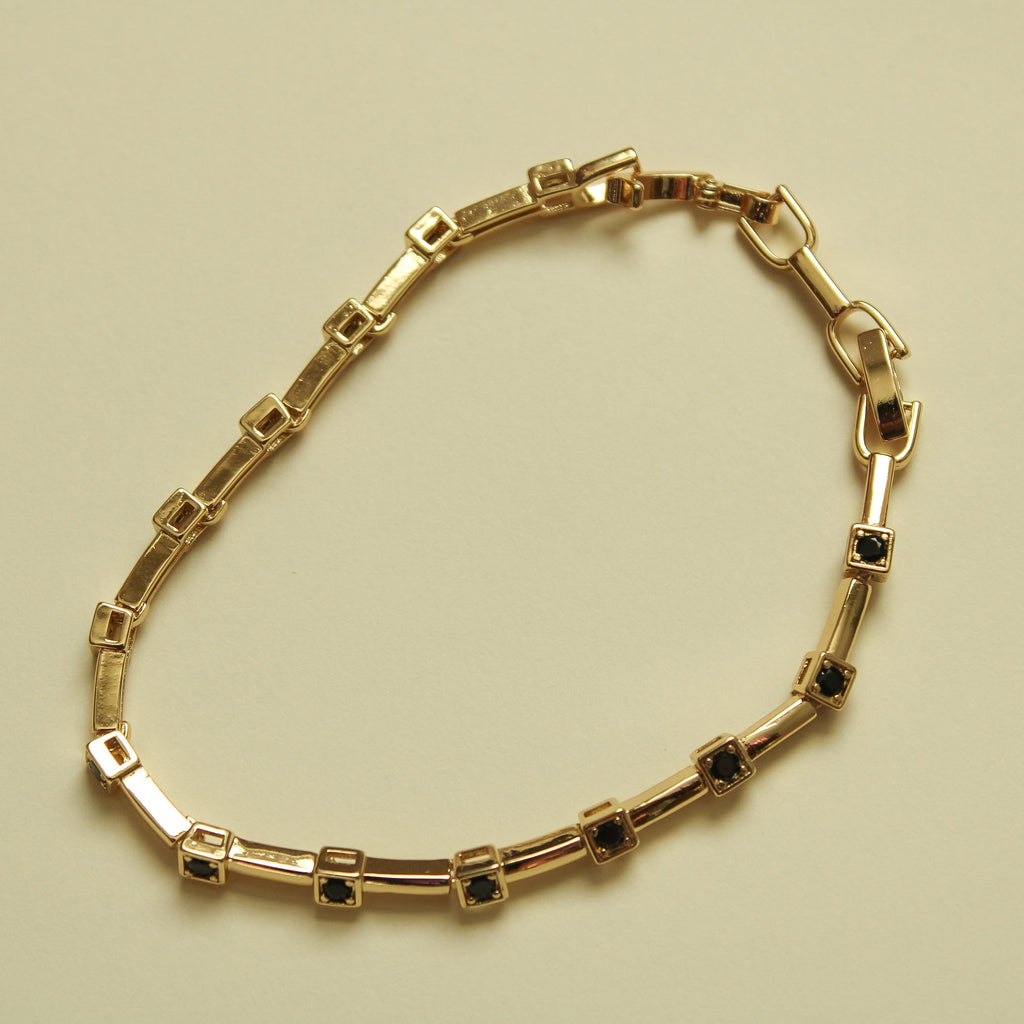Gold bracelet with rectangular links and black CZ bezel stations, hinged clasp
