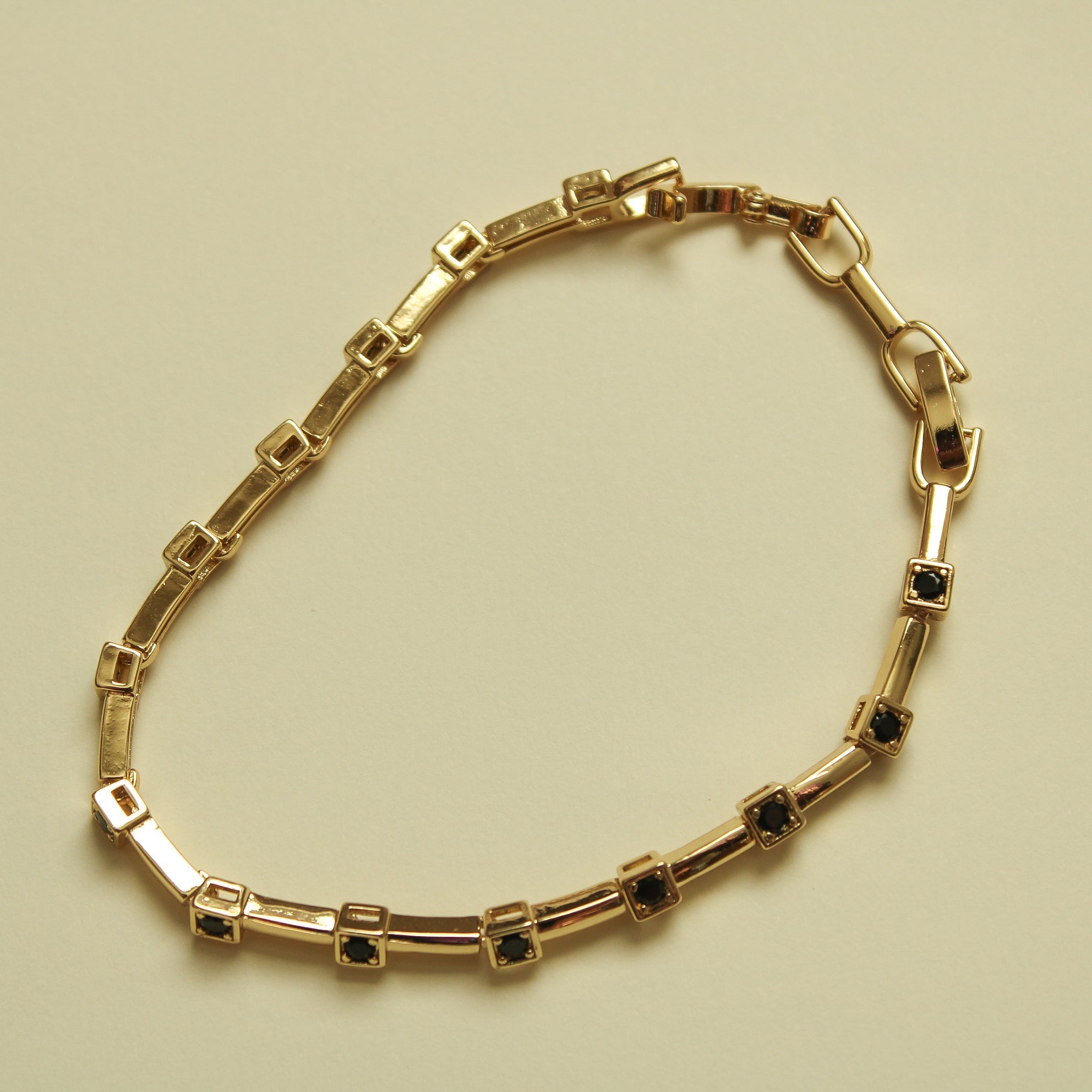 Gold bracelet with rectangular links and black CZ bezel stations, hinged clasp
