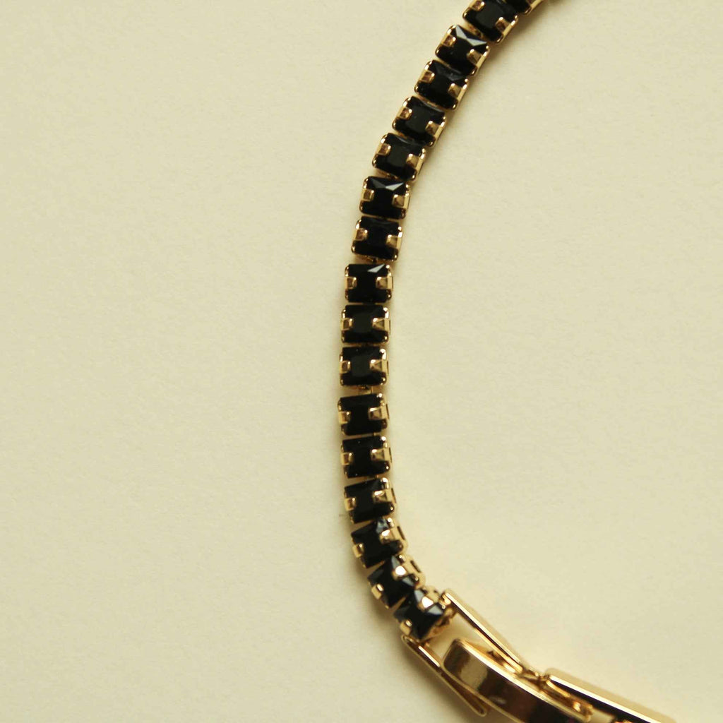 Black tennis bracelet with gold-toned open-link section and bezel-set stones