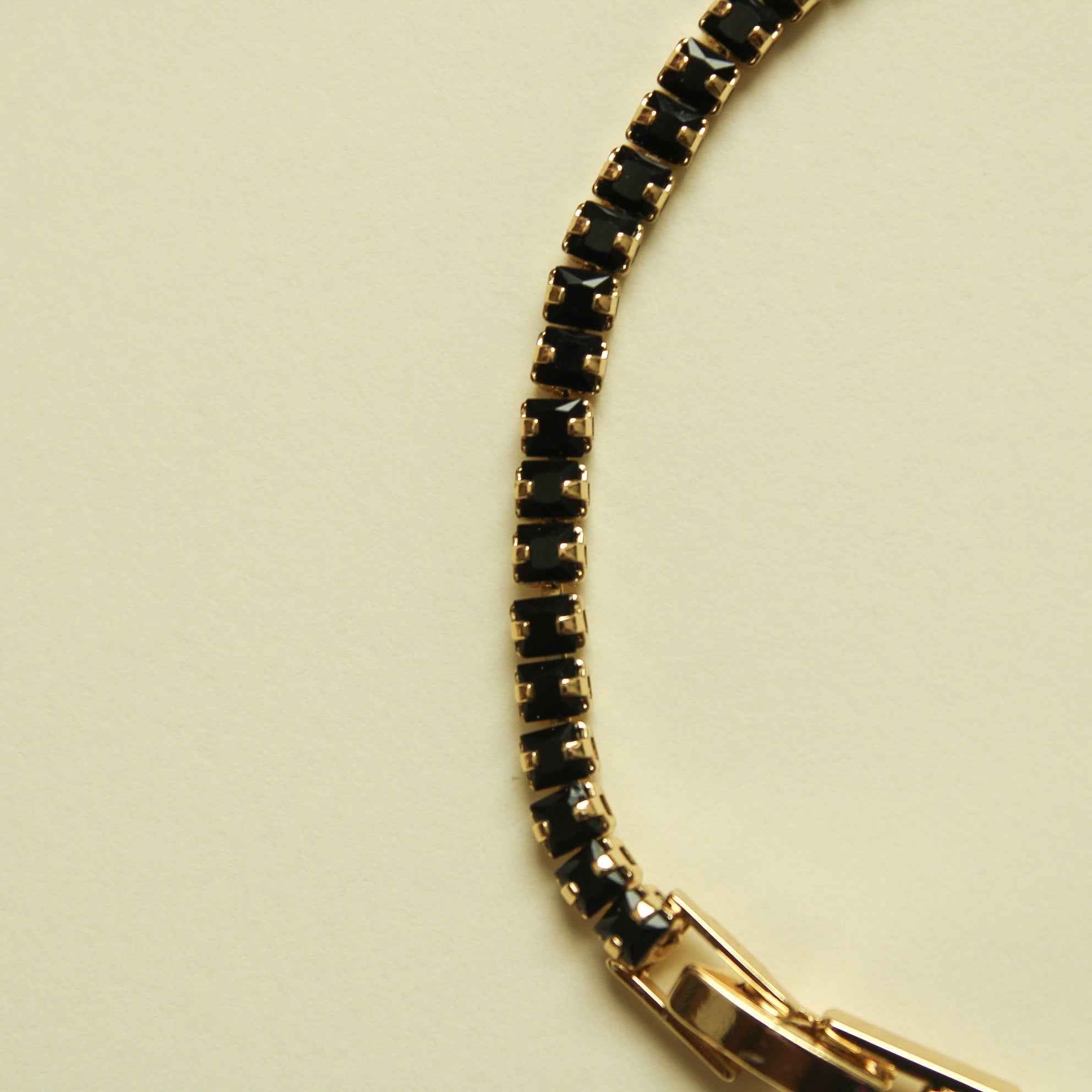 Black tennis bracelet with gold-toned open-link section and bezel-set stones