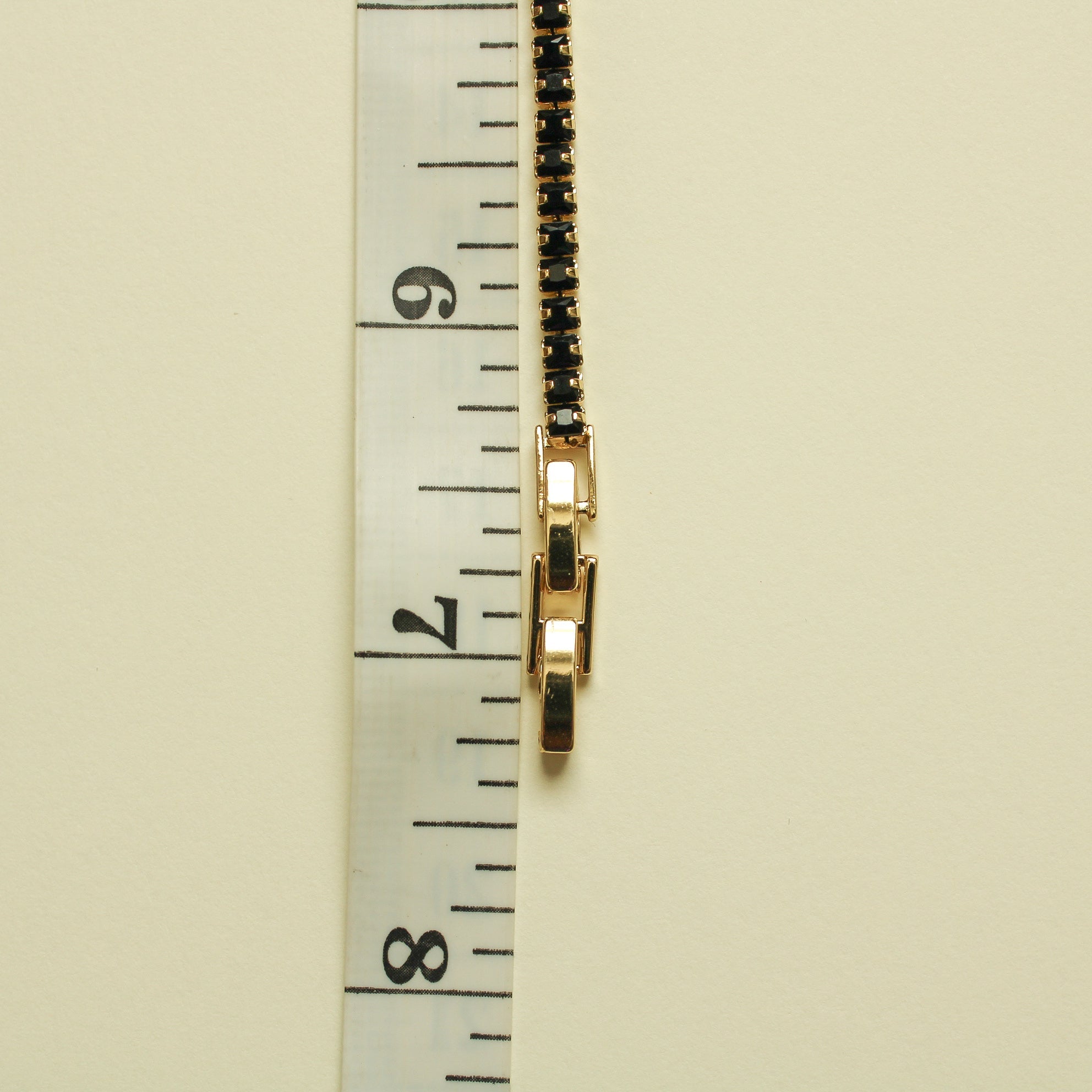 Black tennis bracelet with gold clasp hardware and black stone row, side view