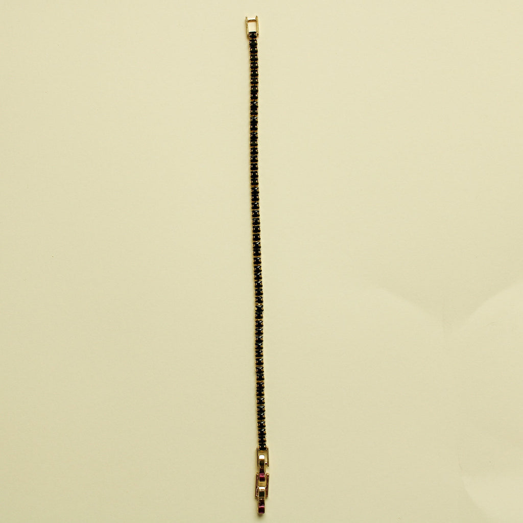Black tennis bracelet with black stone row and small gold clasp end, vertical