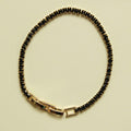 Black tennis bracelet with black stone row and gold-toned bar clasp, full loop