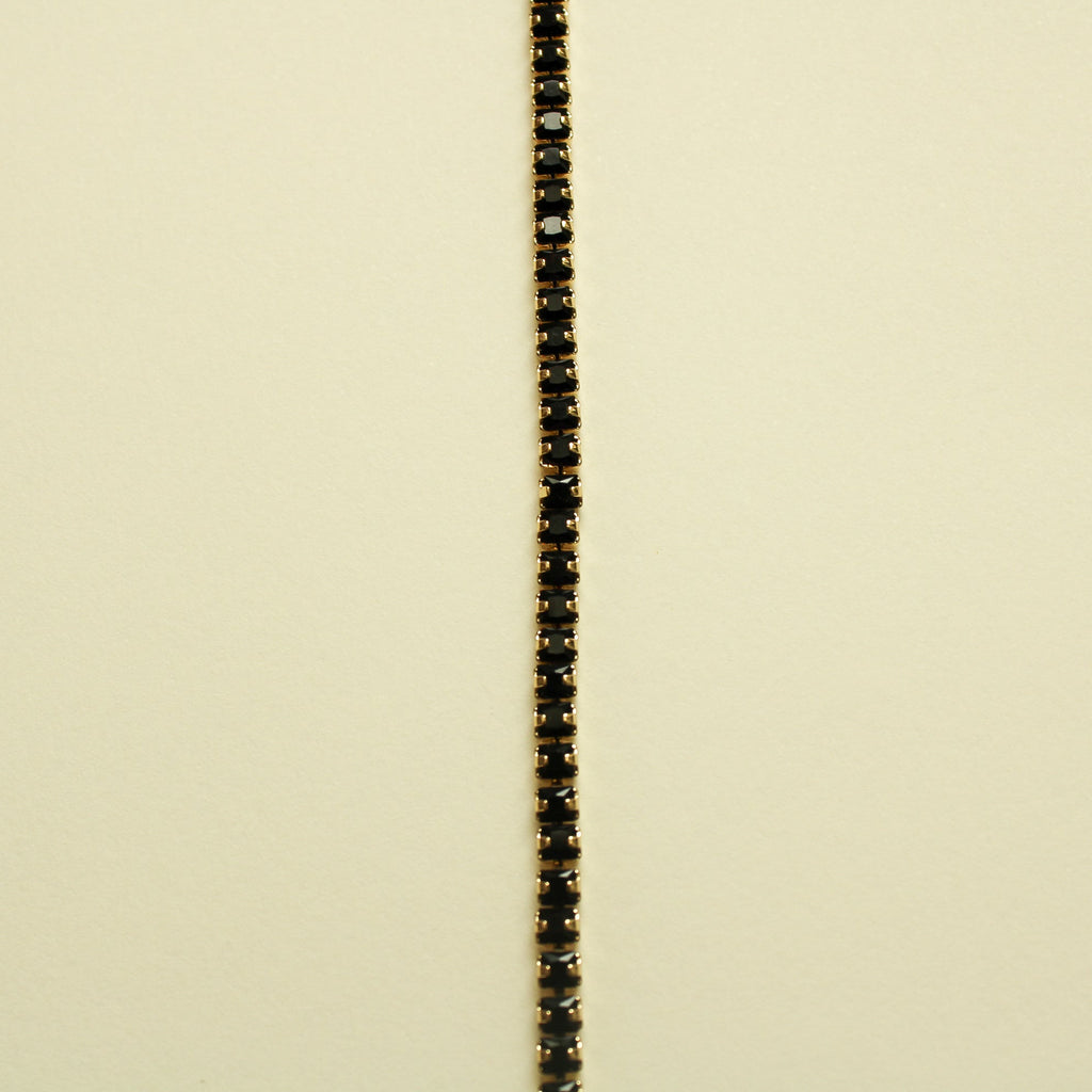 Black tennis bracelet with slim black stone row and gold-toned metal border
