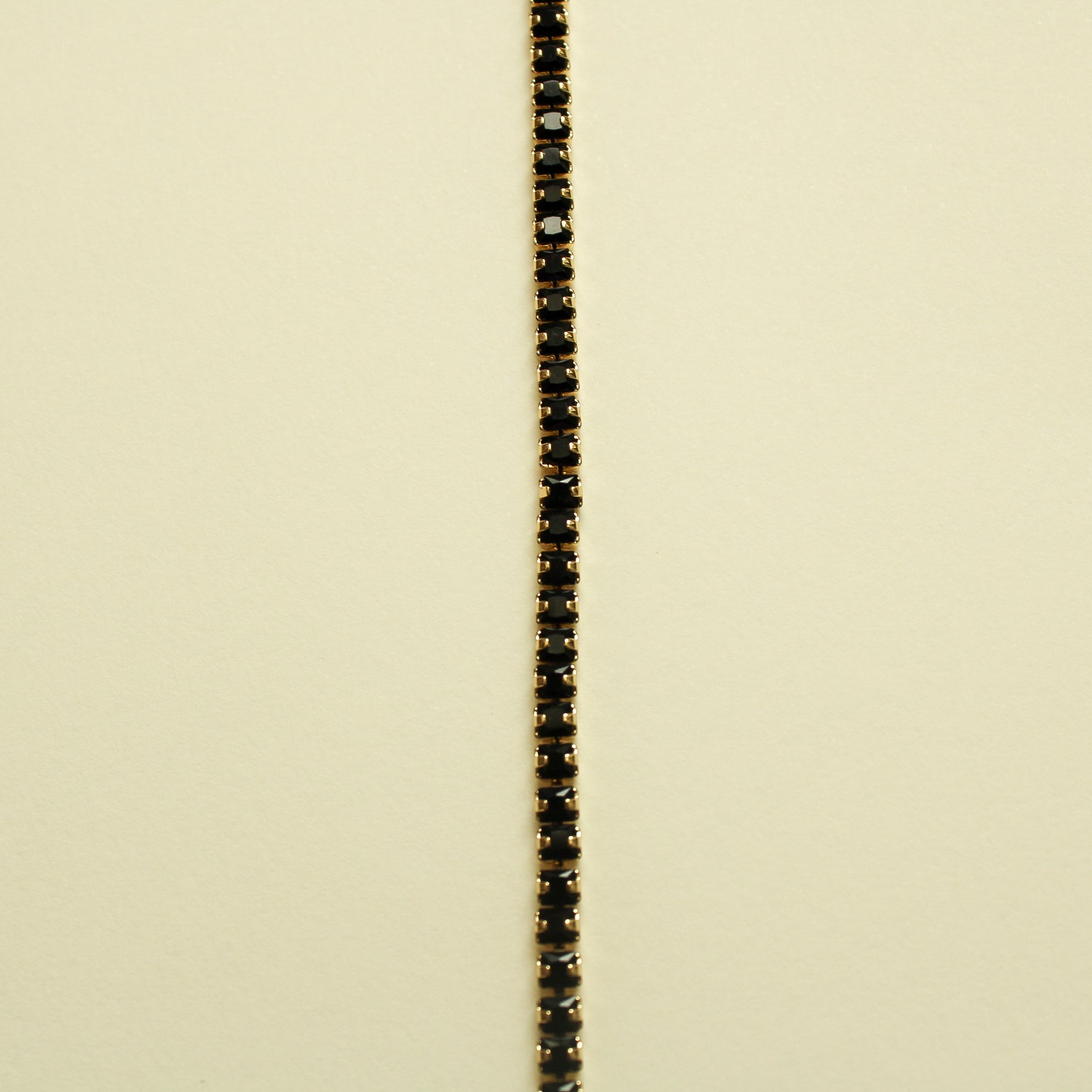 Black tennis bracelet with slim black stone row and gold-toned metal border