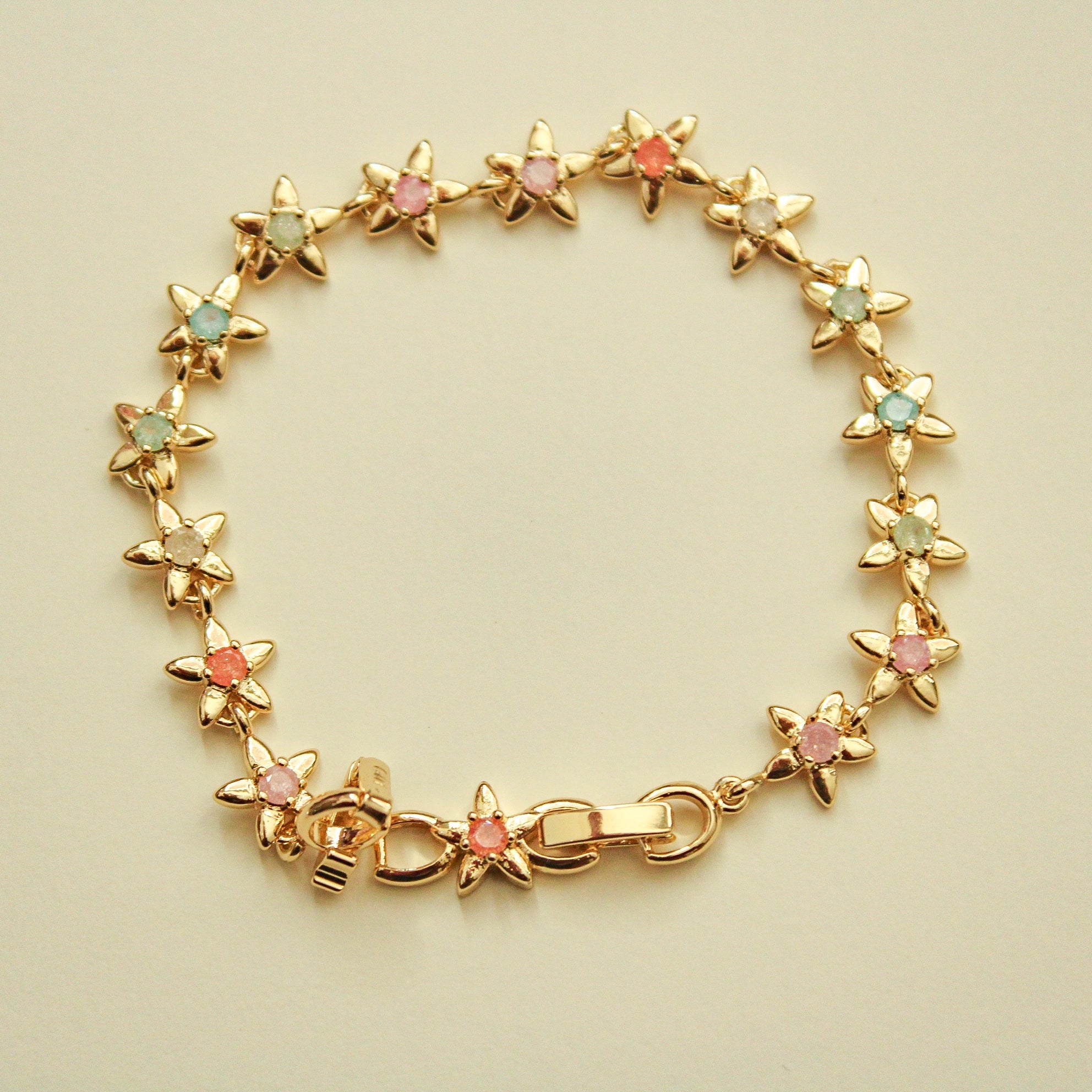Gold flower charm bracelet with colorful stones and round link clasp.