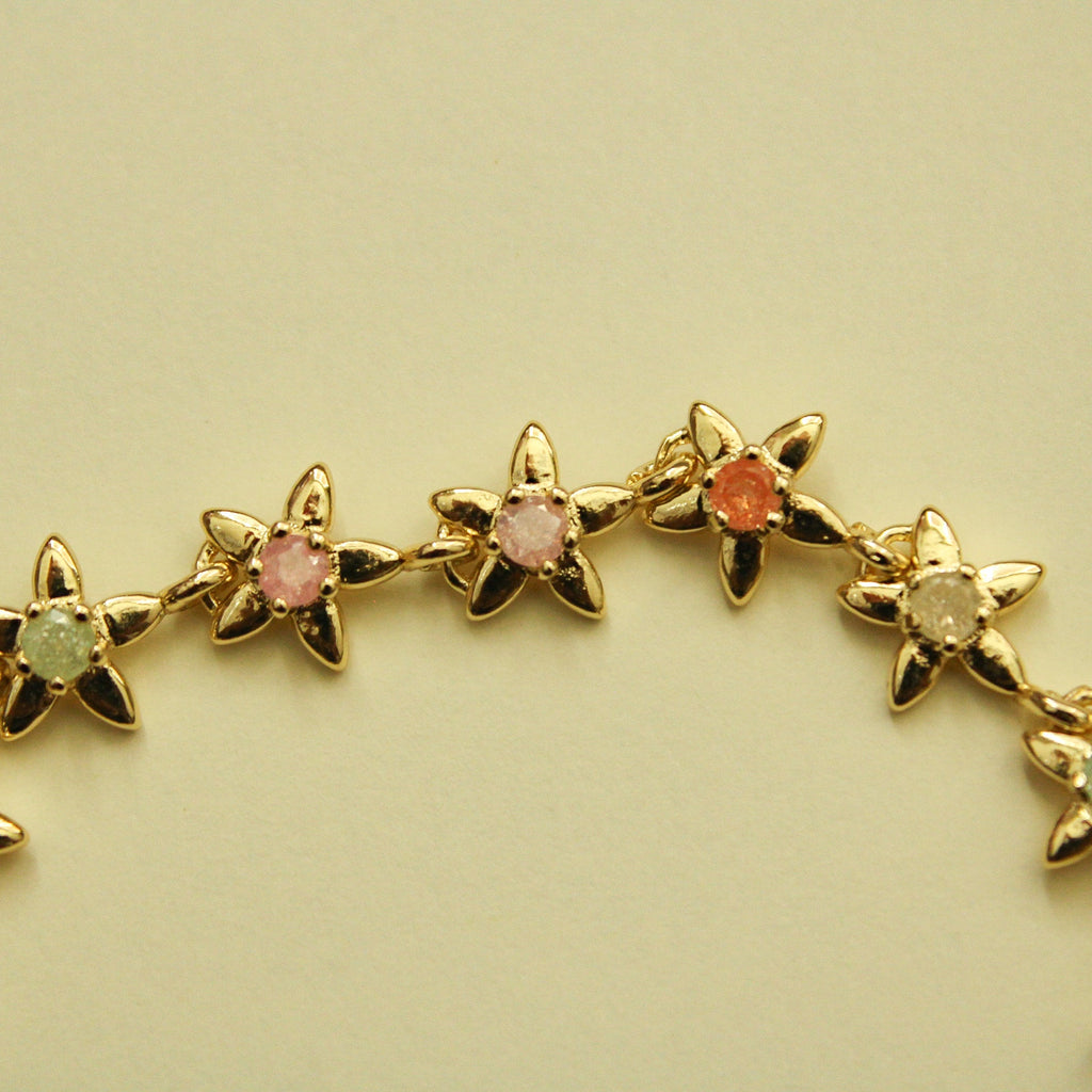 Gold flower charm bracelet strand with mixed pink, green, and orange stones.