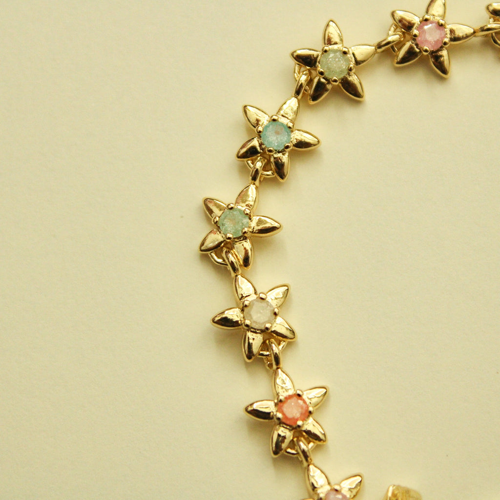 Gold flower charm bracelet with mint green and coral pink flower stones.