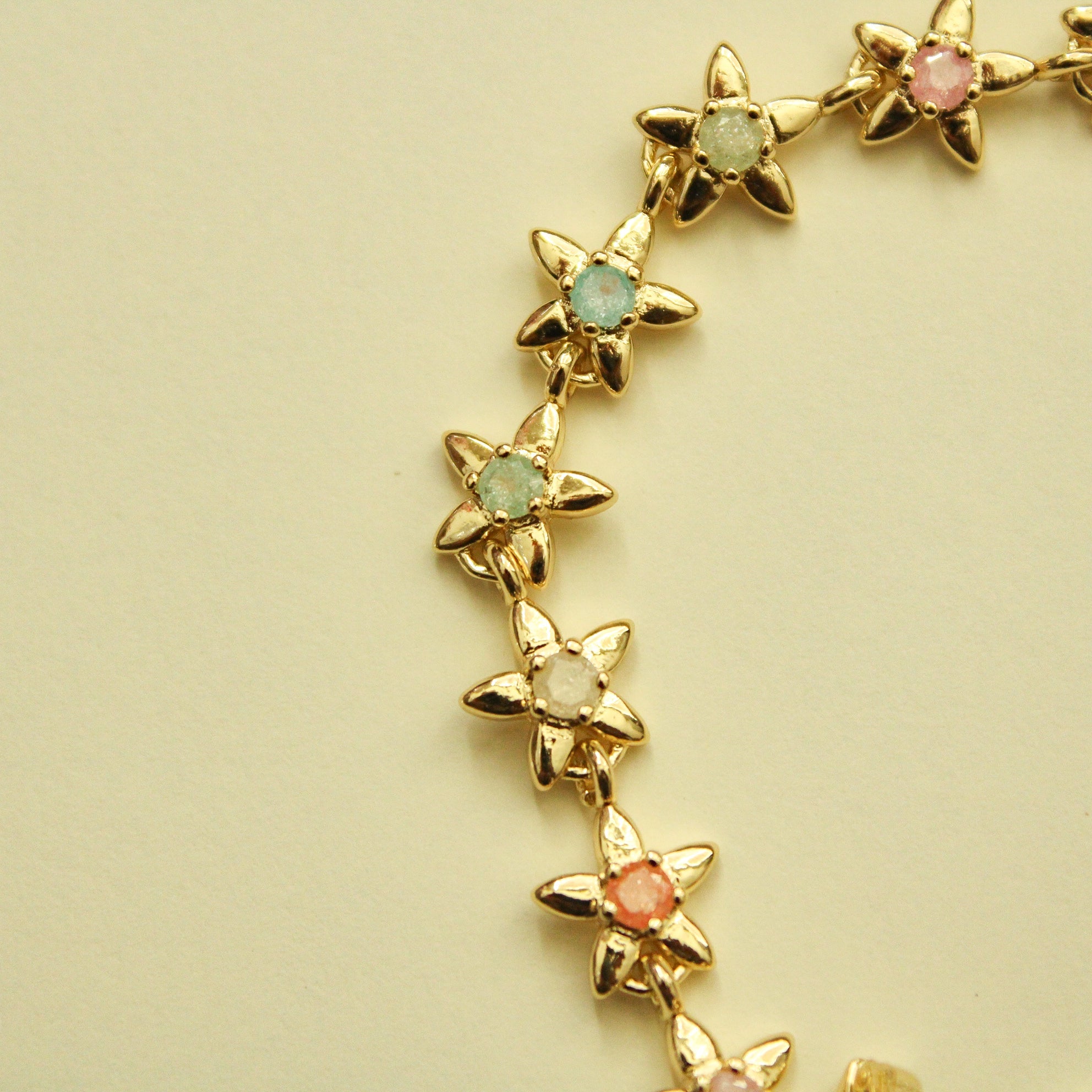 Gold flower charm bracelet with mint green and coral pink flower stones.