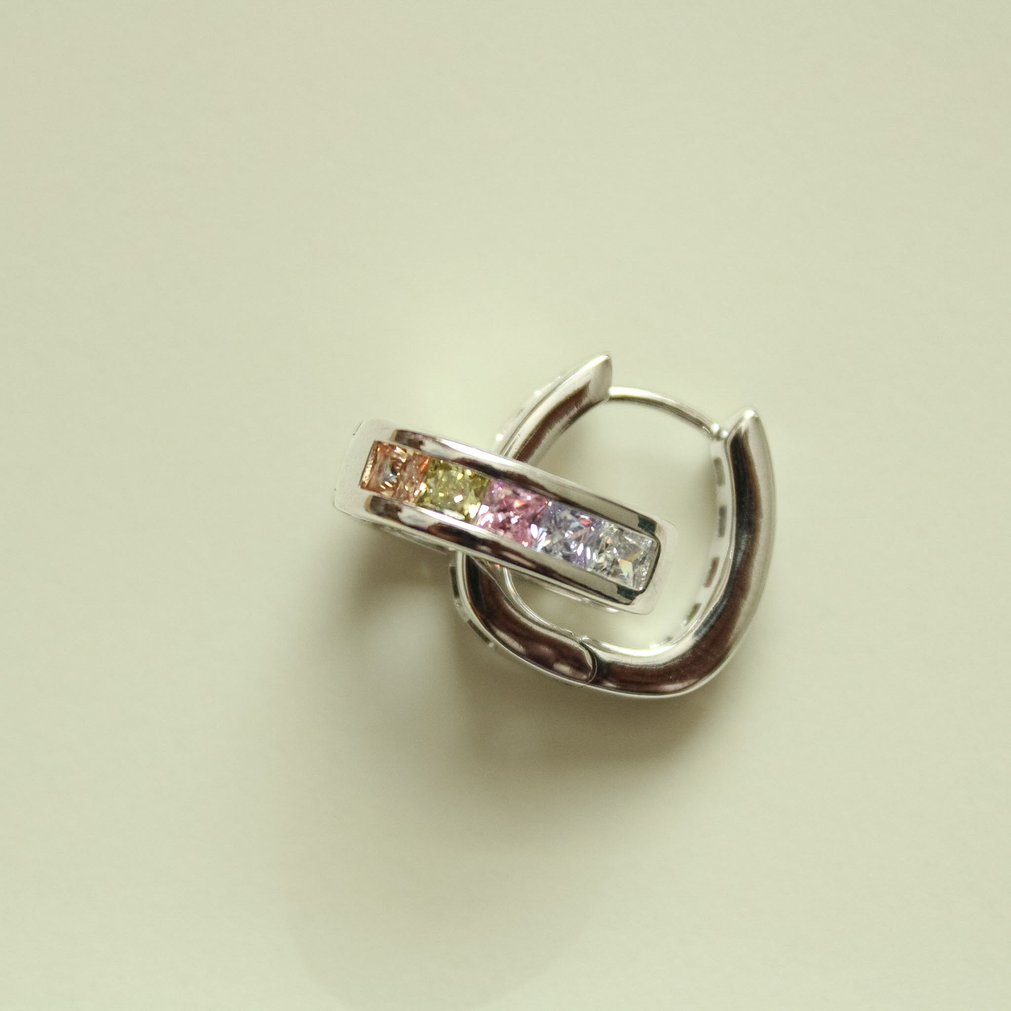 Silver hoop huggie earring with pink center stone and clear side accents