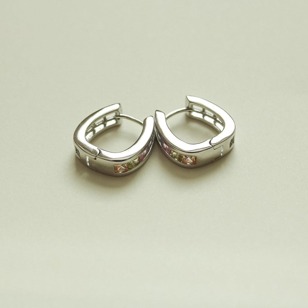 Pair of silver hoop huggie earrings, open front view with clear stones