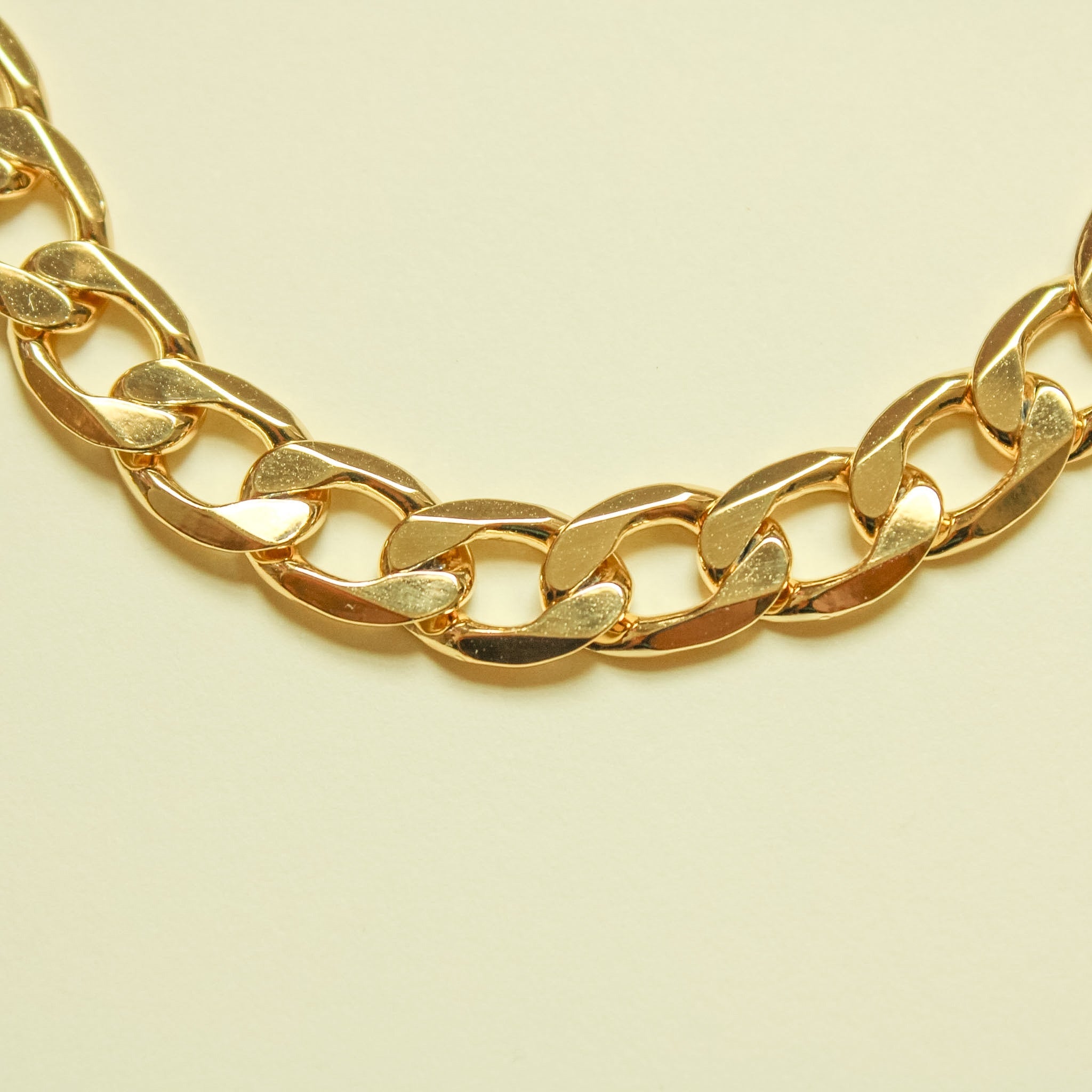 Chunky Cuban link 14K gold chain necklace, close-up of curved polished links