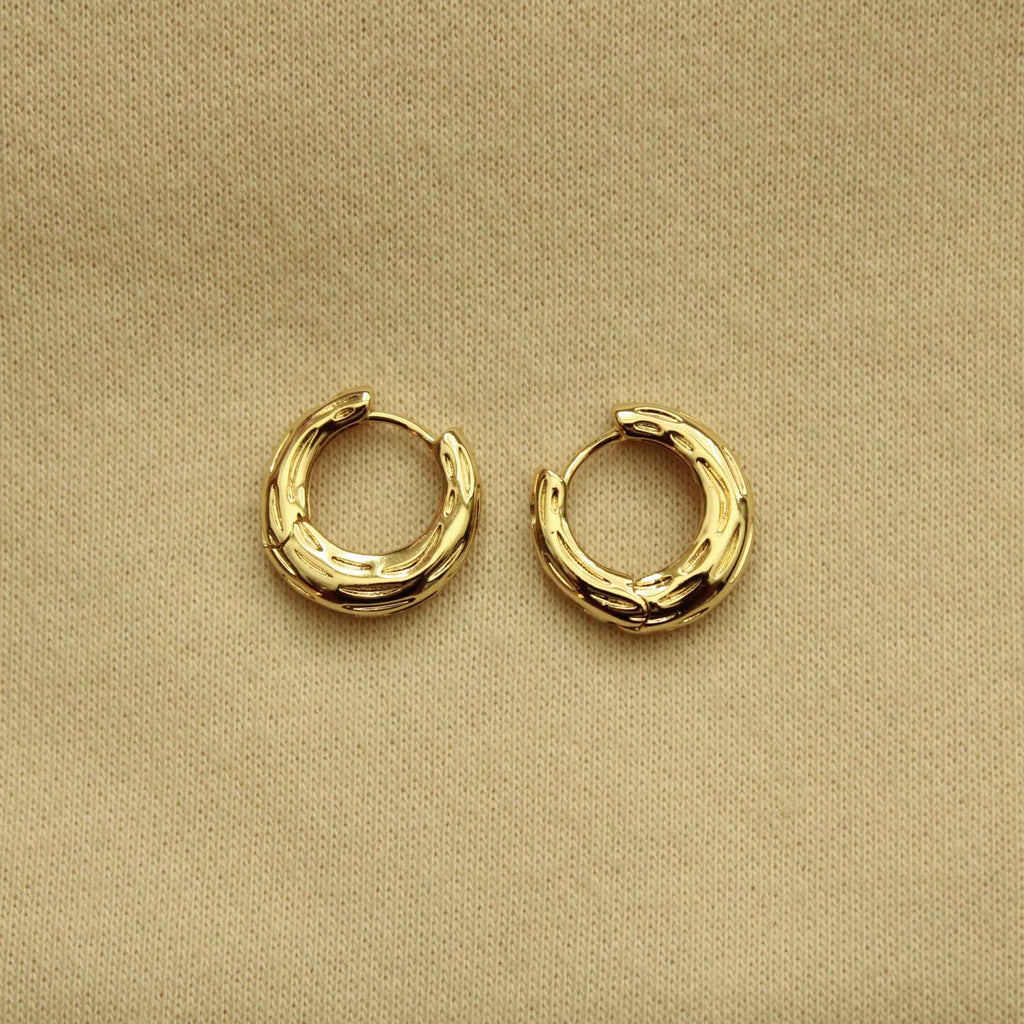 Gold huggie hoop earrings with ridged textured bands, small rounded hoops