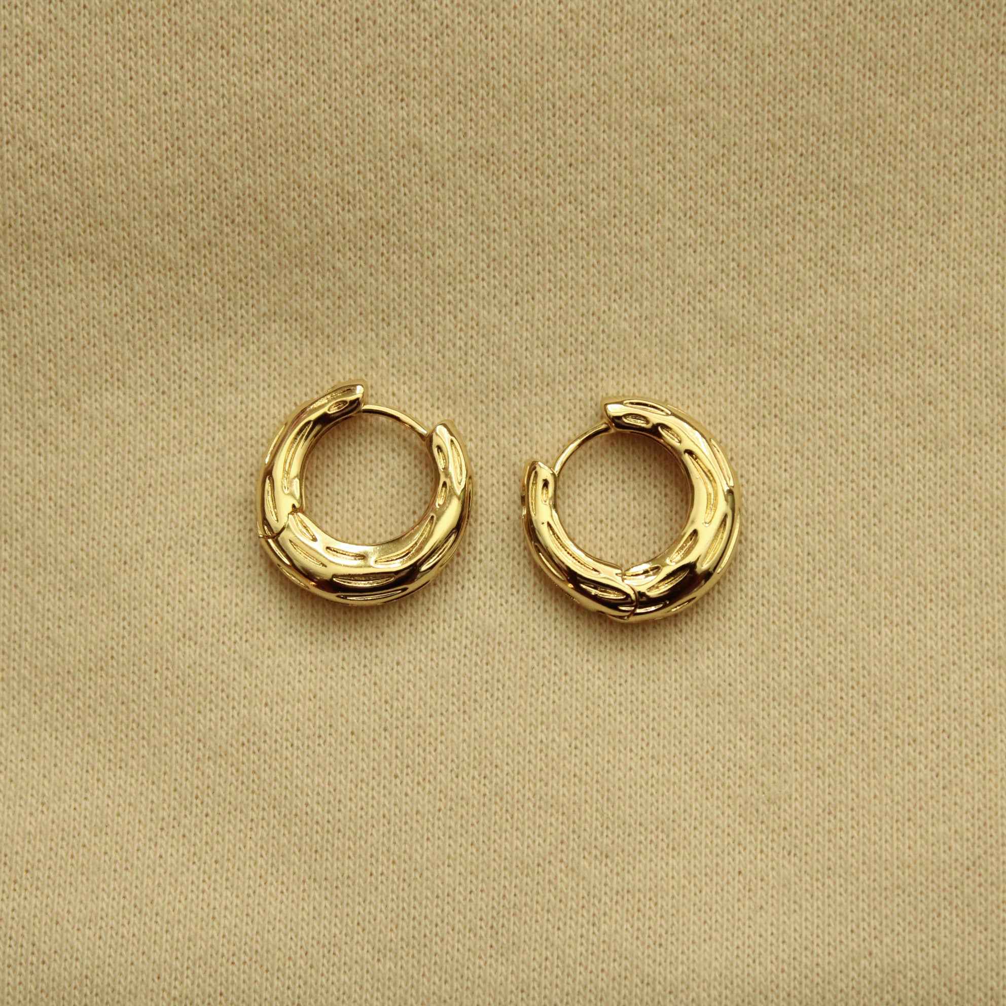 Gold huggie hoop earrings with ridged textured bands, small rounded hoops