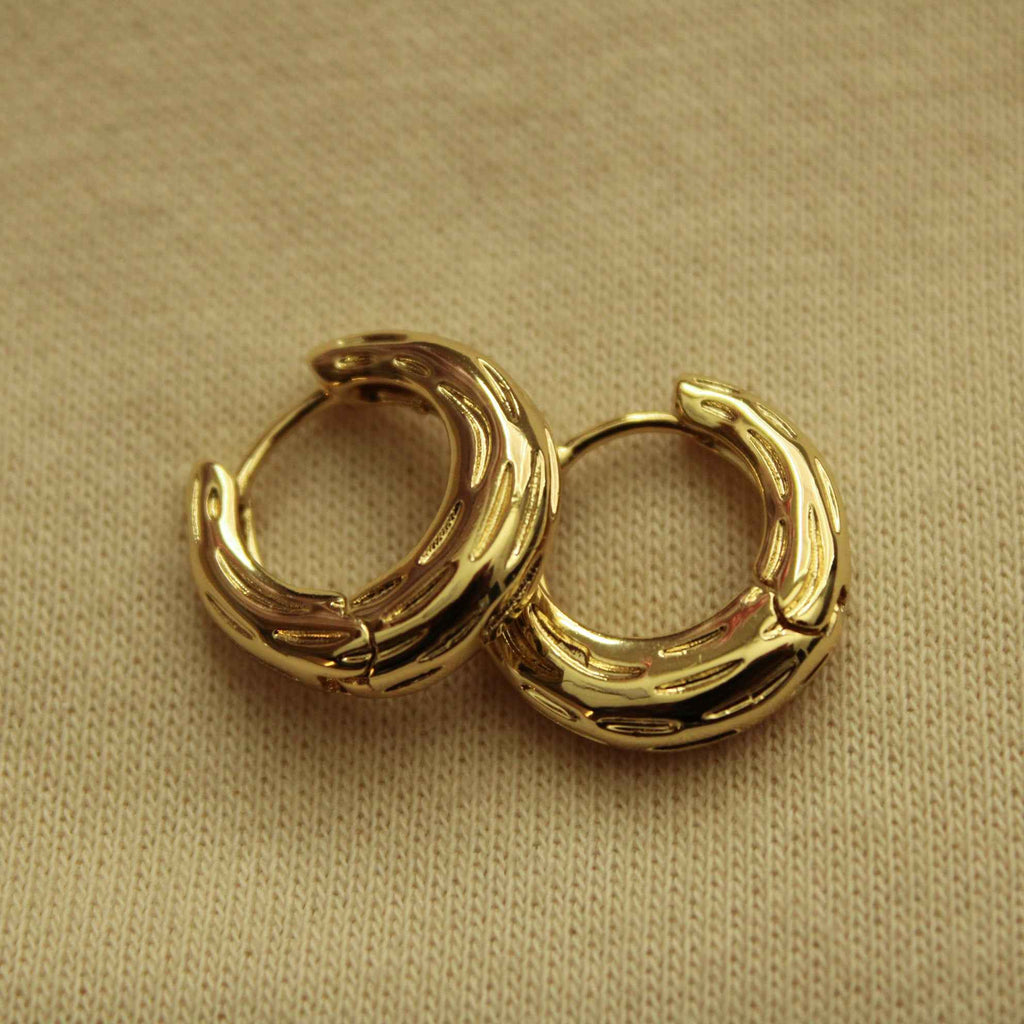Gold chunky huggie hoop earrings with ribbed texture, curved profile