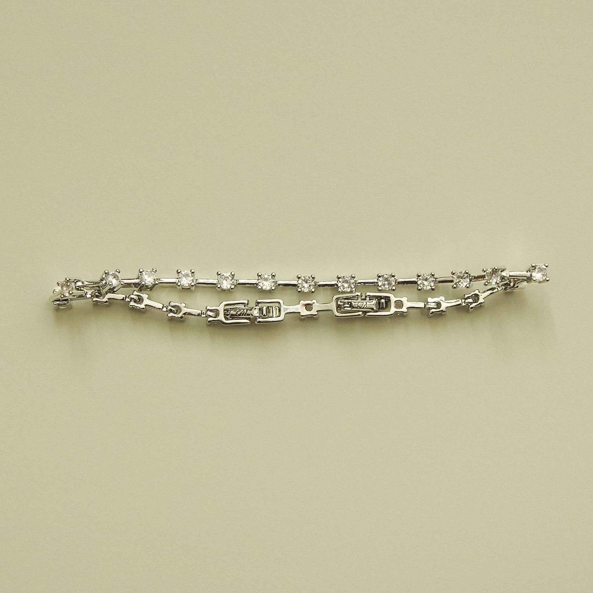 Clear CZ station bracelet laid flat, round clear stones on a silver-tone link chain
