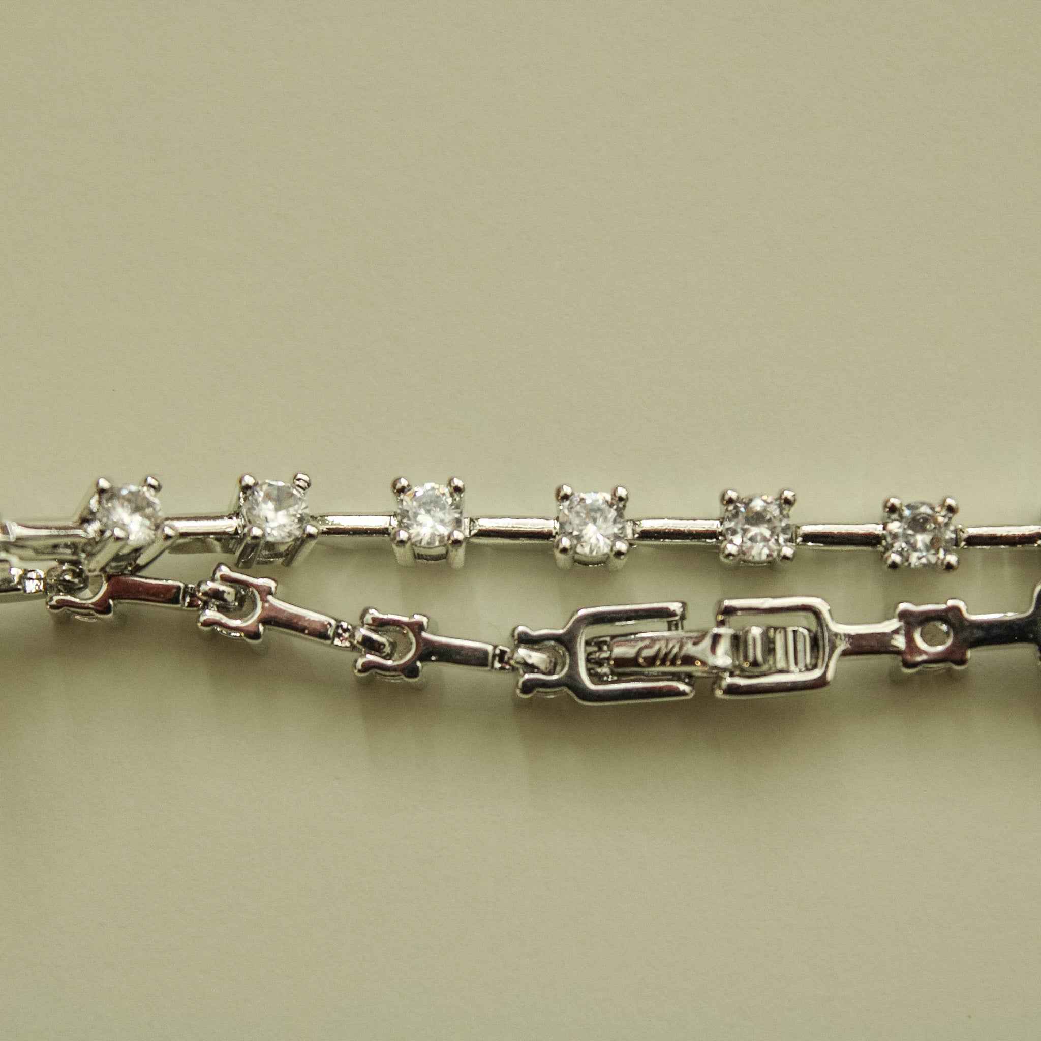 Clear CZ station bracelet side view showing round clear stones, prong stations, and clasp