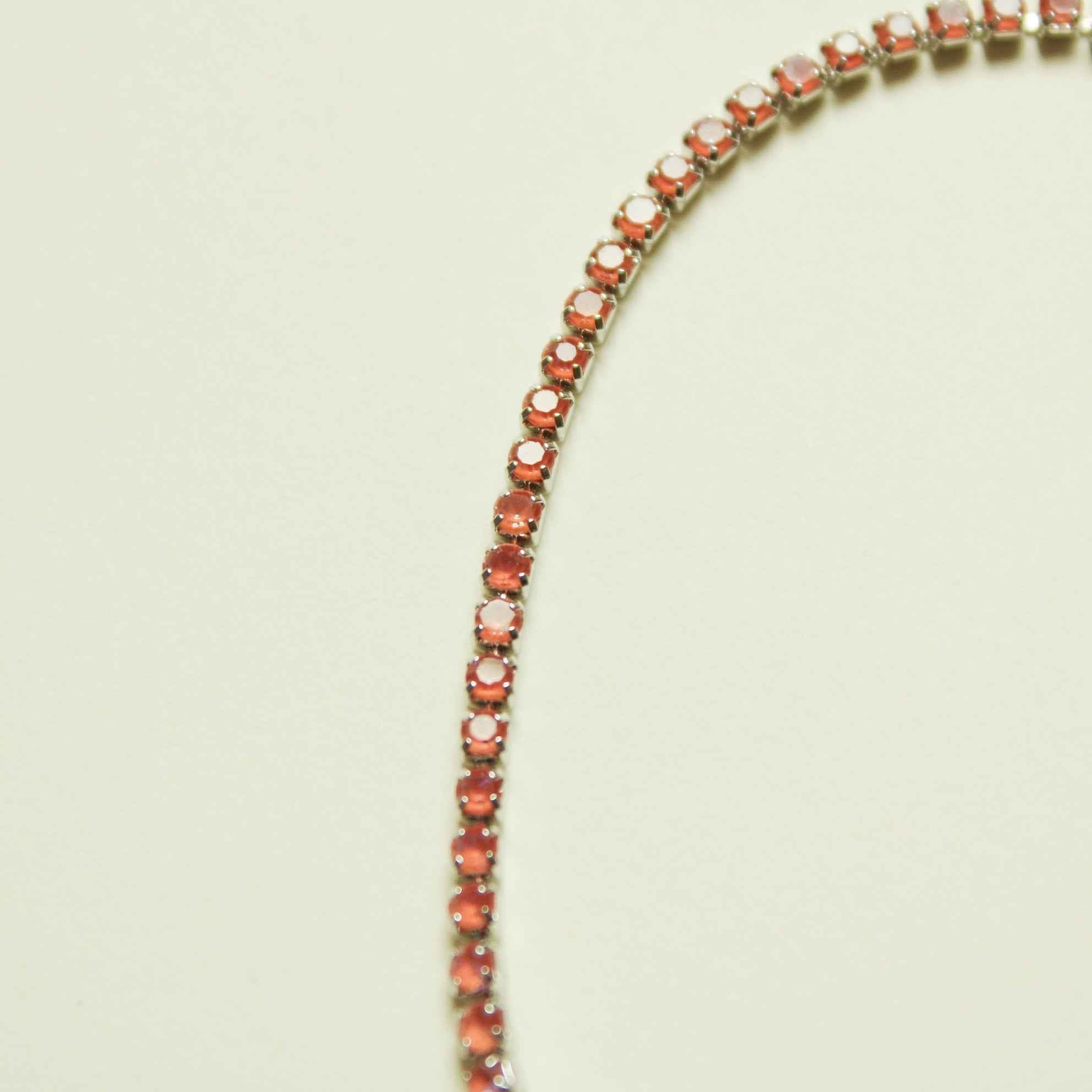 Tennis bracelet with color-shifting coral orange round stones in silver-tone settings