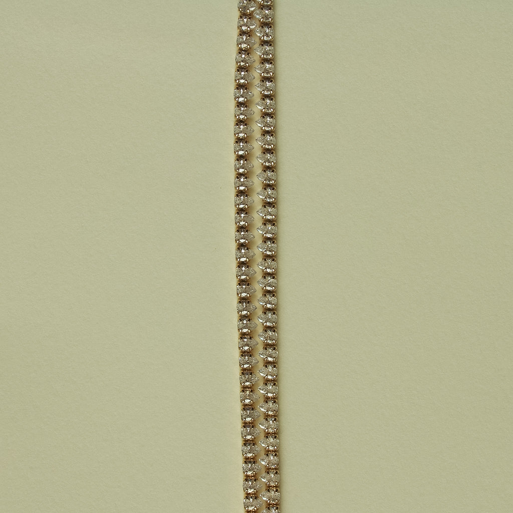 Gold-tone double-row tennis bracelet with clear CZ stones, close-up view.