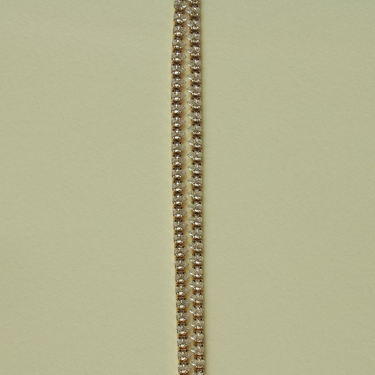 Gold-tone double-row tennis bracelet with clear CZ stones, close-up view.