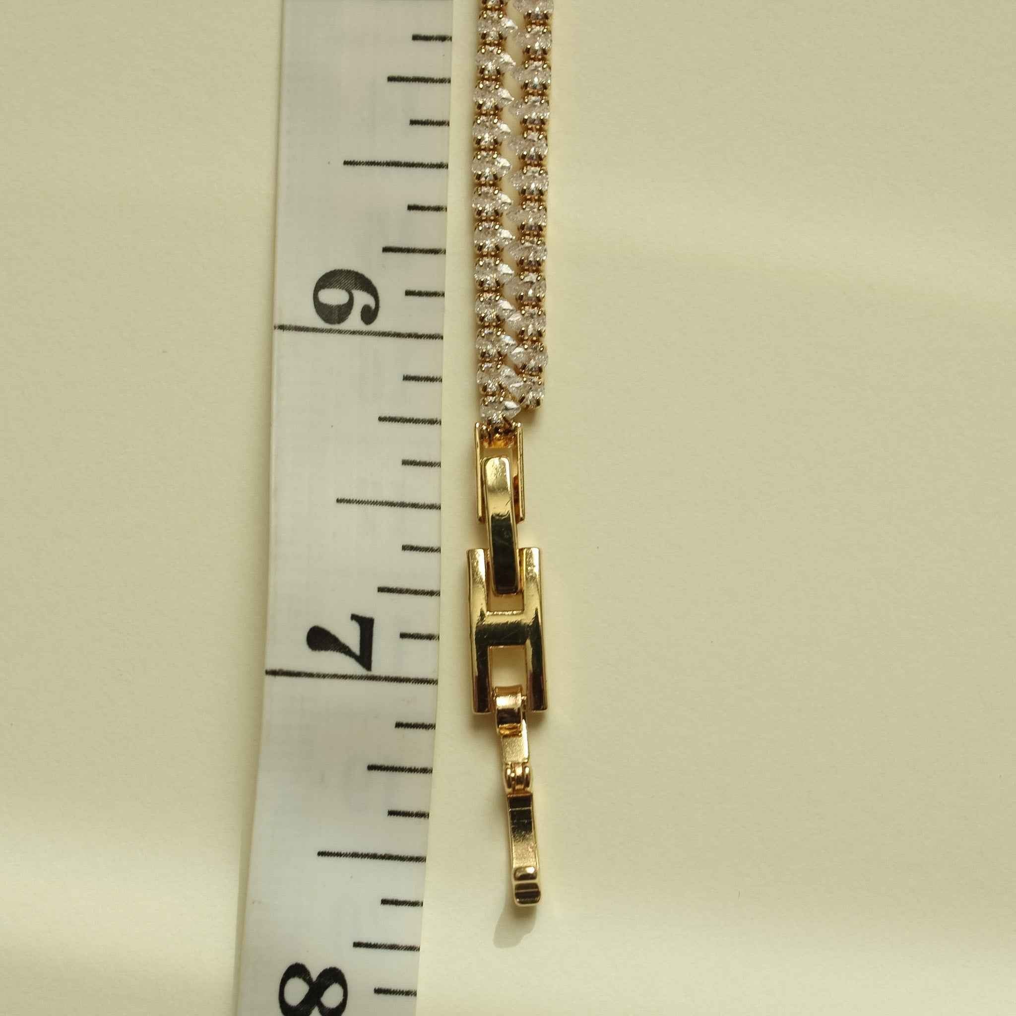 Gold-tone double-row tennis bracelet clasp with clear CZ pavé, side view.
