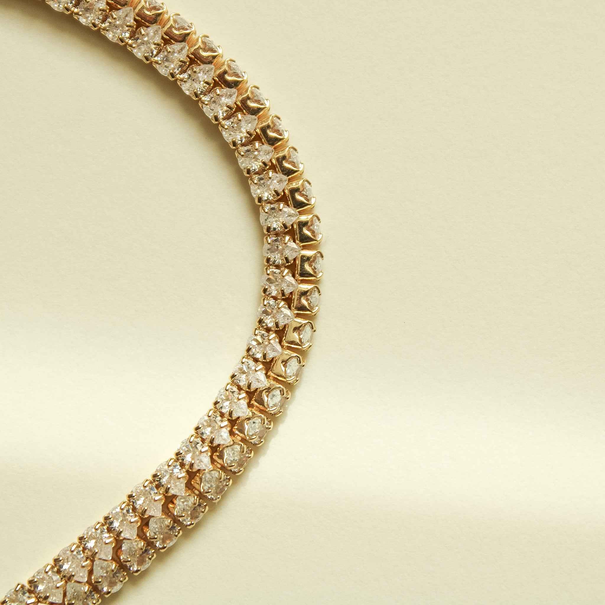 Gold-tone tennis bracelet with clear CZ link details along the double row.