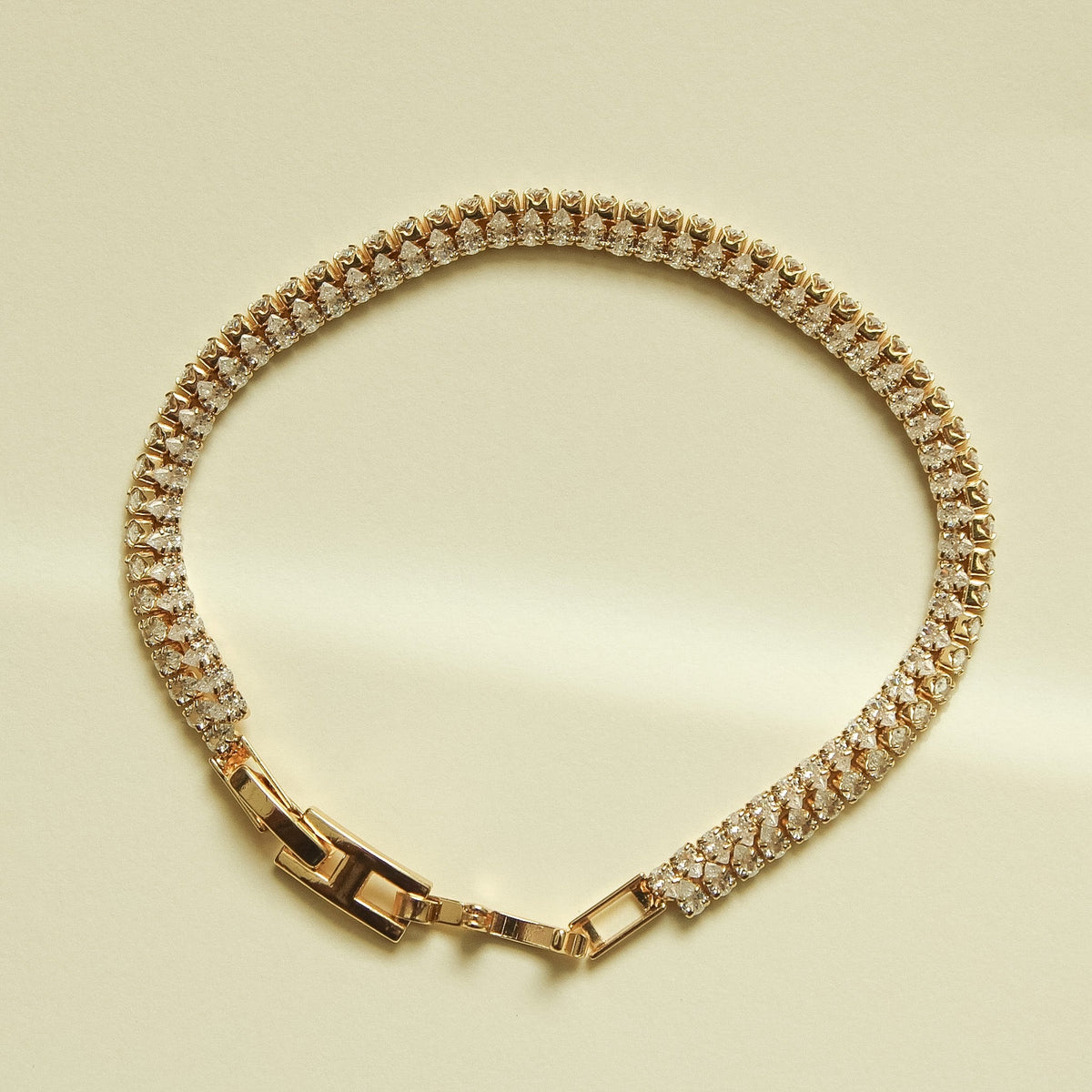 Gold-tone double-row tennis bracelet with clear CZ stones and box clasp.
