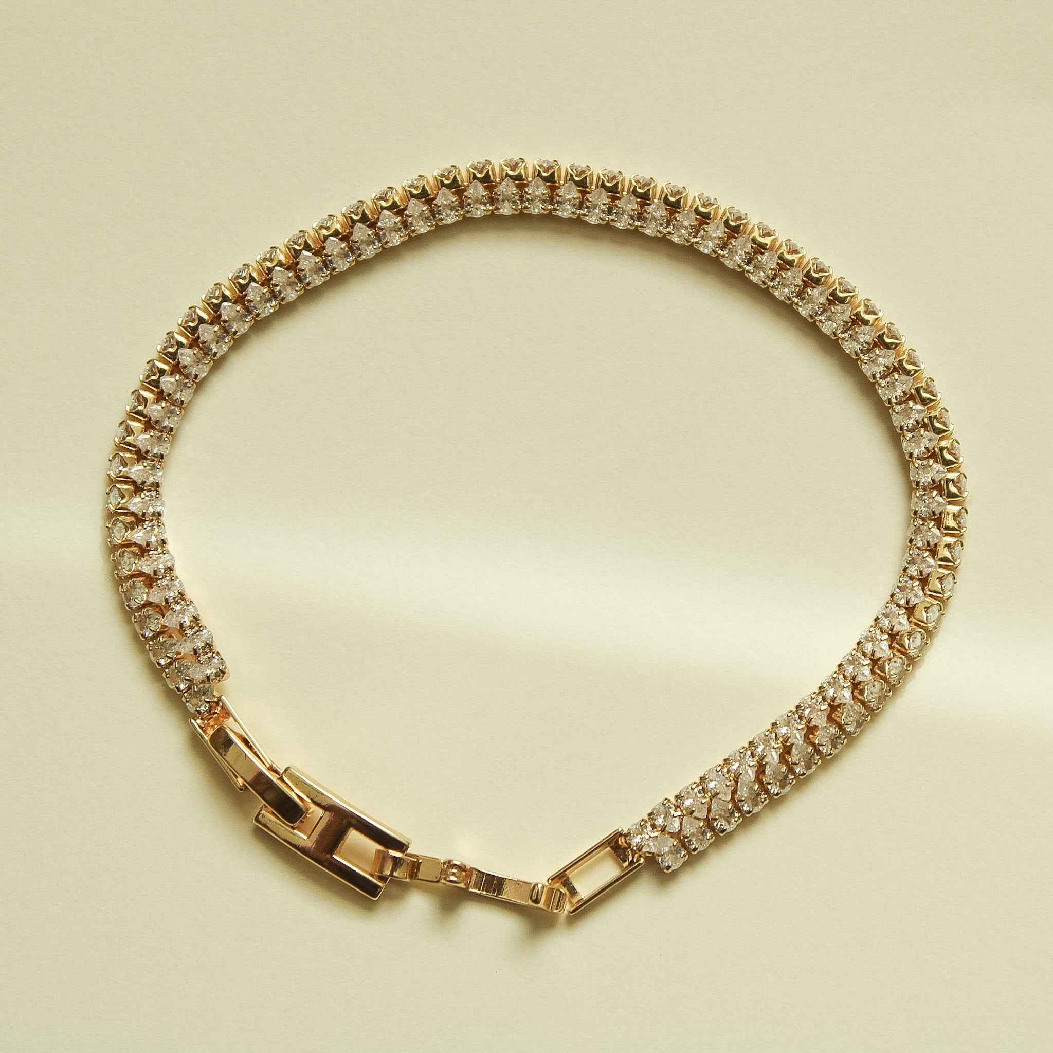 Gold-tone double-row tennis bracelet with clear CZ stones and box clasp, front view.