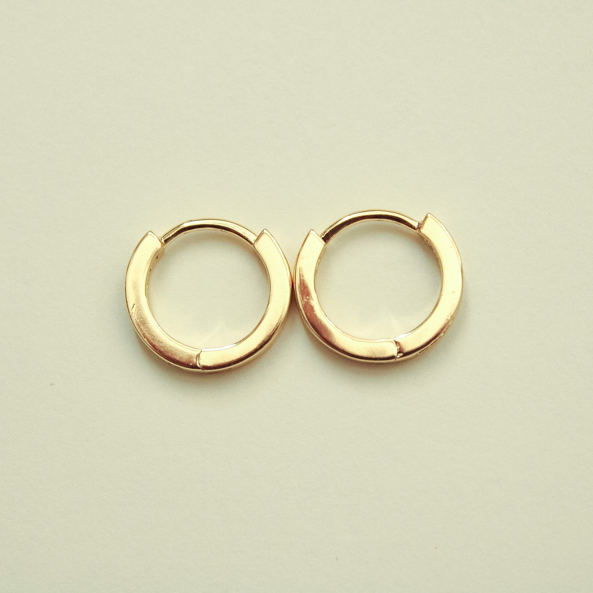 Gold-tone mini huggie hoop earrings with round hinged shape and open back