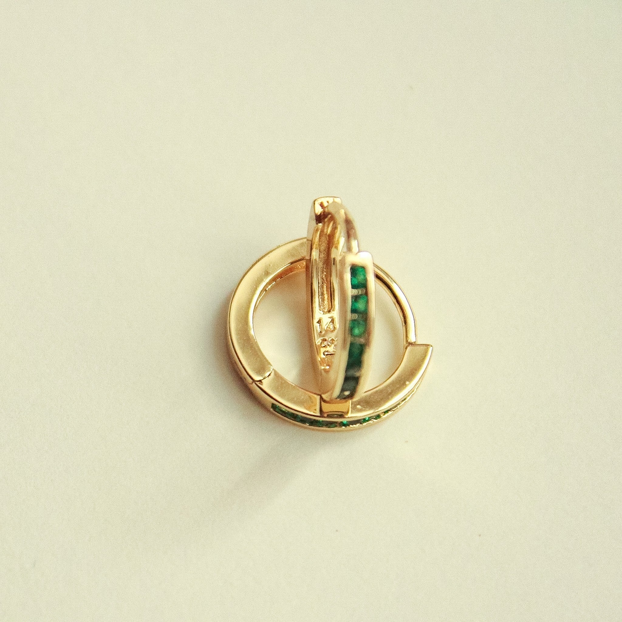 Gold-tone mini huggie hoop earrings, front view with green CZ bar center