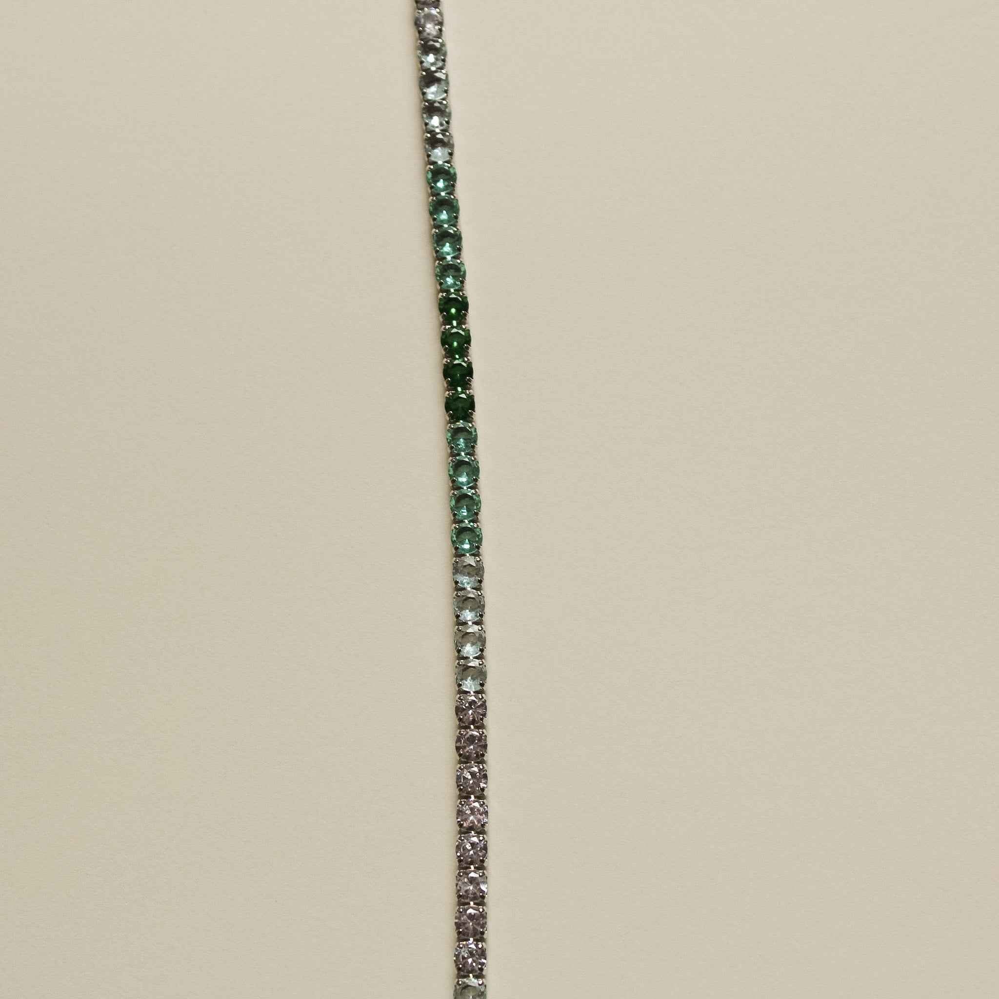 Tennis bracelet with narrow line of small green and clear pavé stones