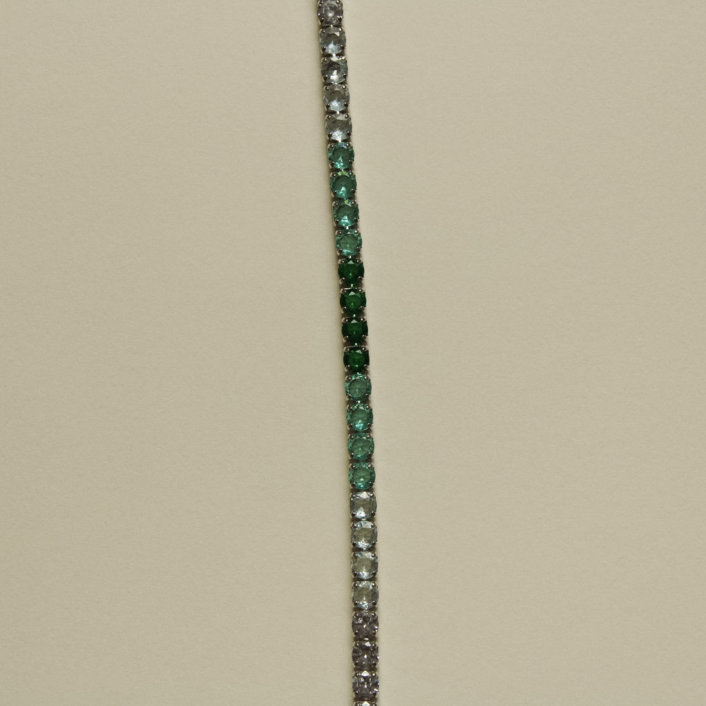 Tennis bracelet with vertical line of green and clear stones, no clasp visible